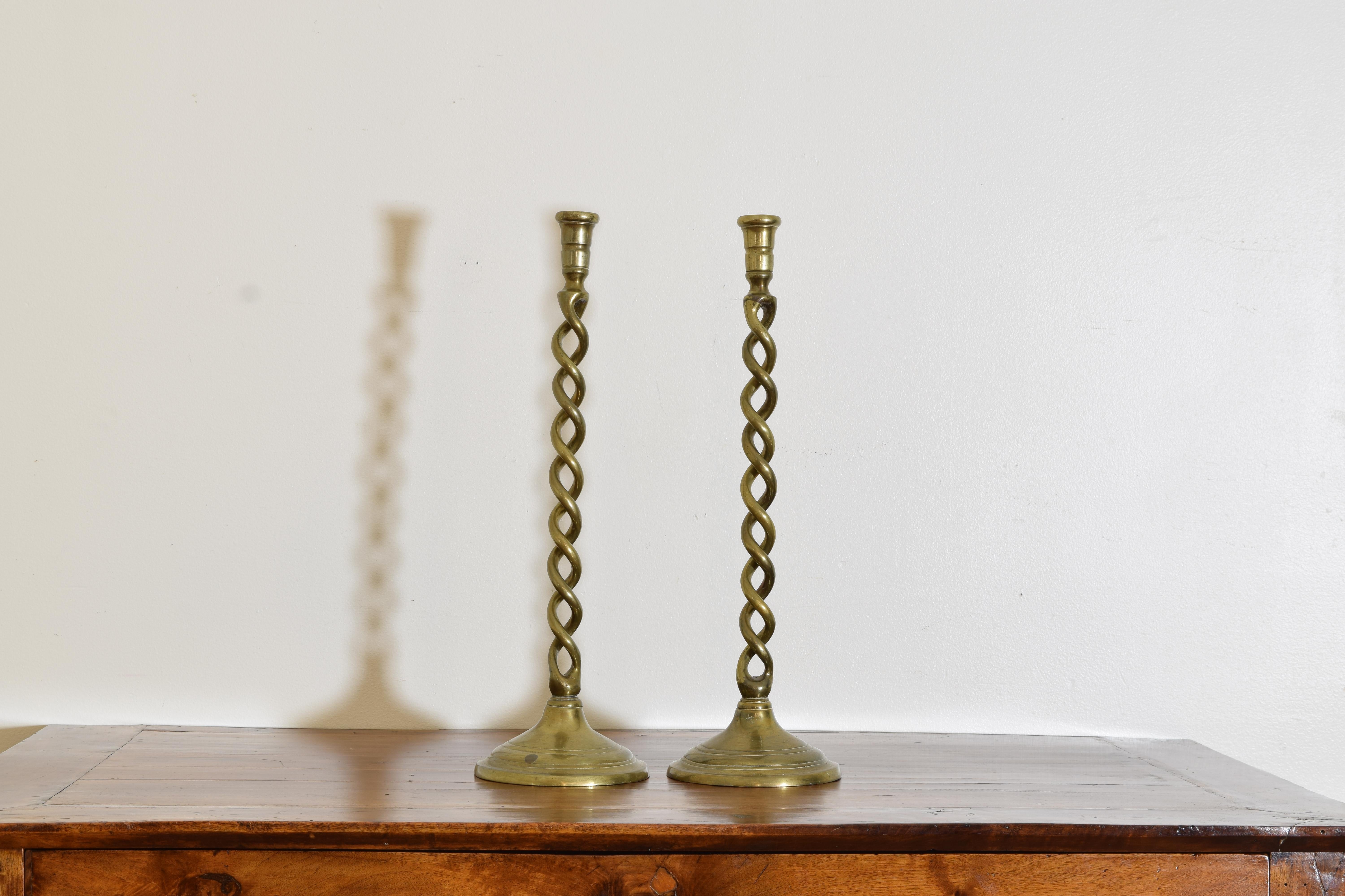 Having small candle cups atop twisting brass bodies and raised on elevated circular bases, easily wired as lamps