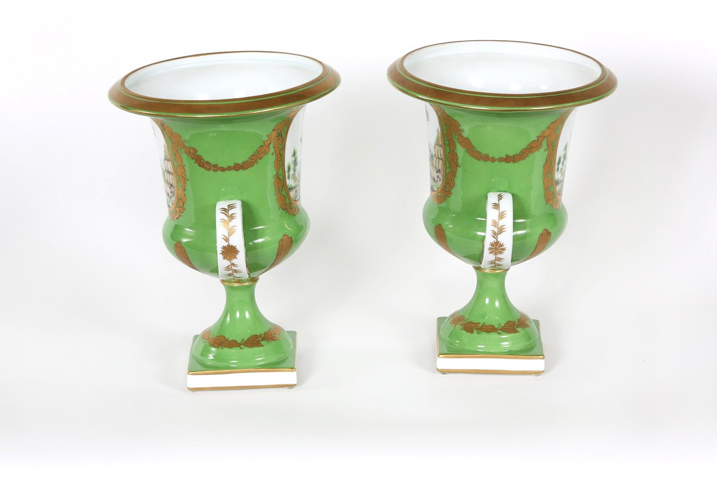 Pair of English porcelain floral decorative vases/urn with exterior gilt gold design details and side handles . Each vase / urn is in good condition with minor wear consistent with age / use . Each vase stand about 12 inches tall X 9 inches