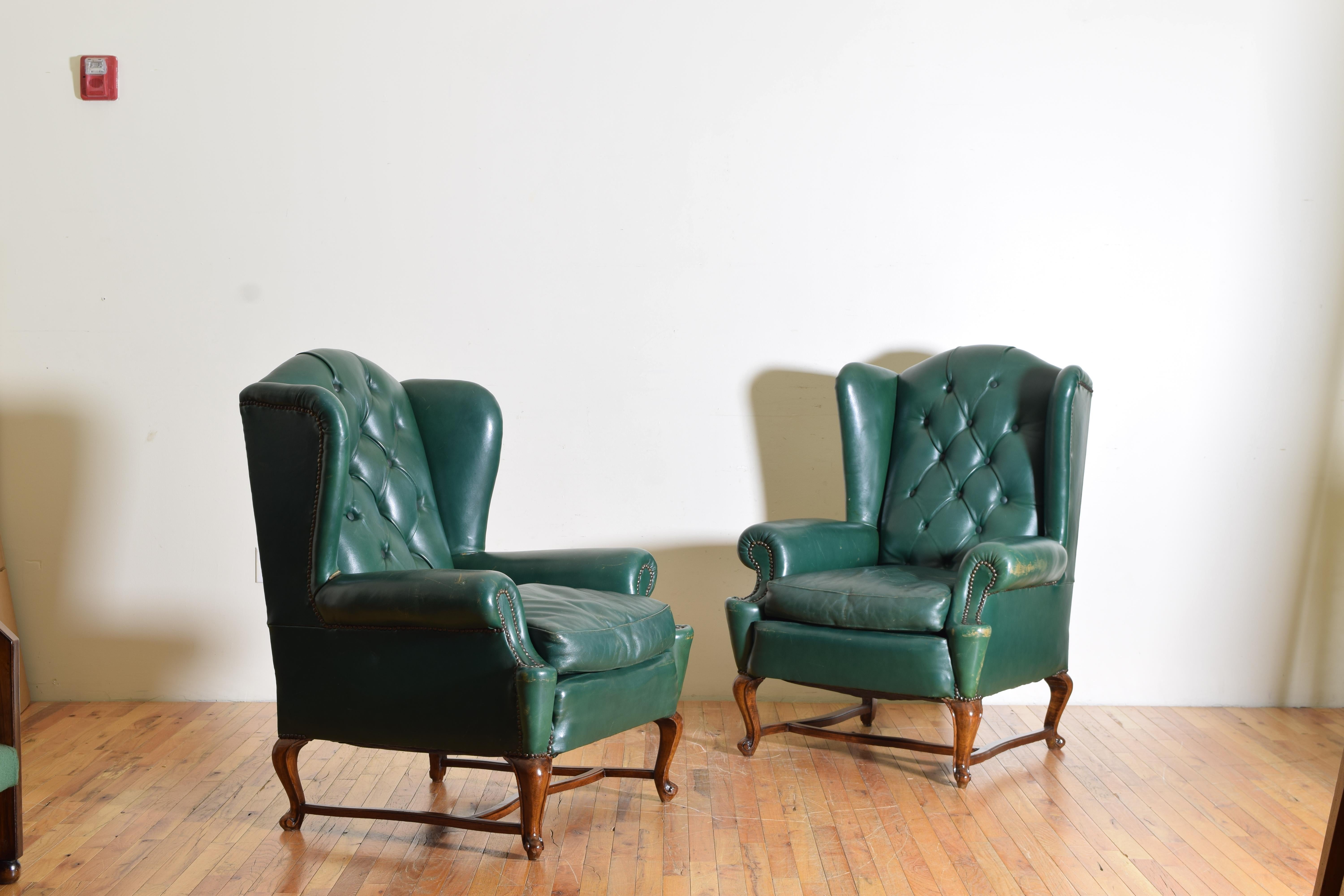 large in scale and entirely covered in leather, the backrests in tufted leather, with loose down filled cushions, raised on cabriole legs joined by stretchers and having pad feet