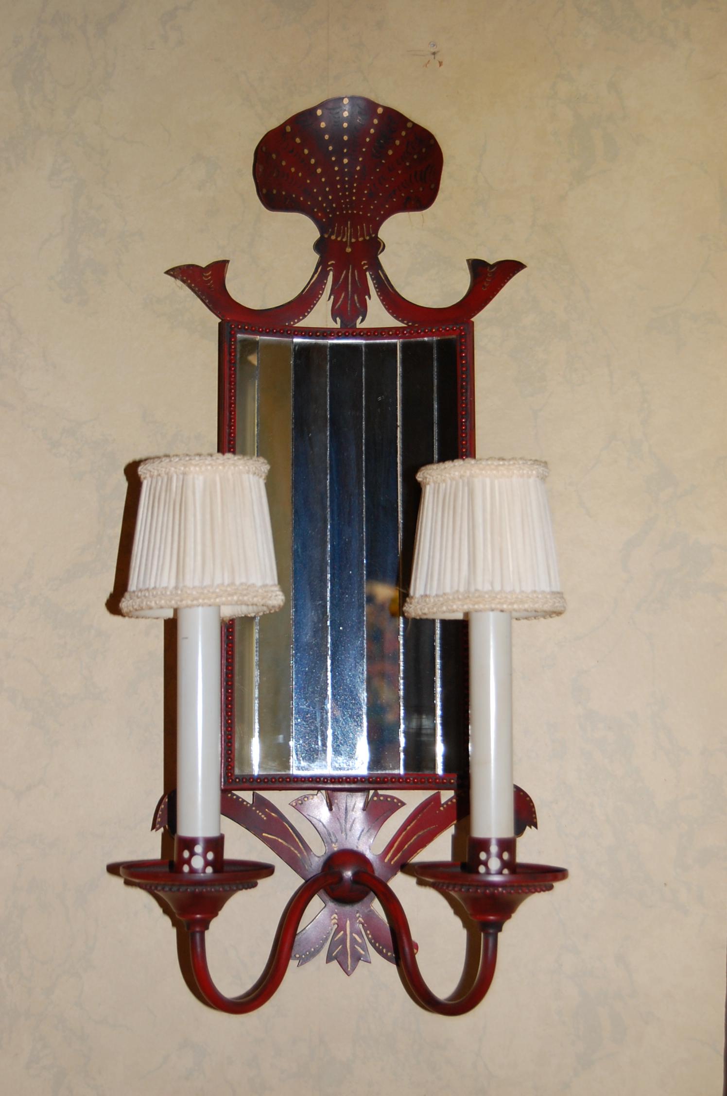 Pair of red painted and decorated tole sconces with narrow pieces of mirror set into the curved back plate in original painted finish, circa 1900. A shaped Scallop shell sits atop the back plate and is nicely detailed using paint. This pair of