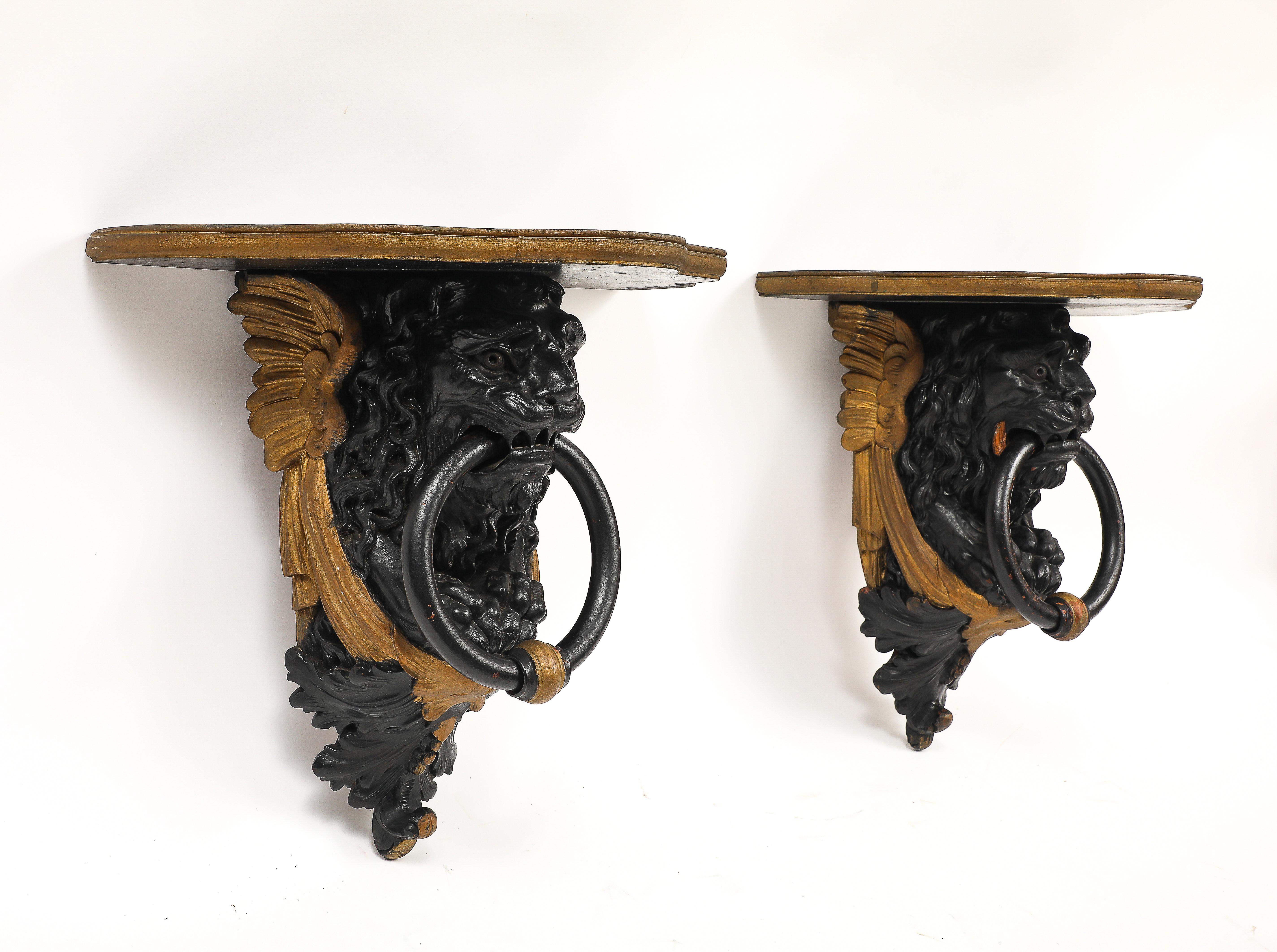 Intagliato a mano Coppia di mensole da parete inglesi Regency in lacca nera e oro con maschere di leone e anelli in vendita