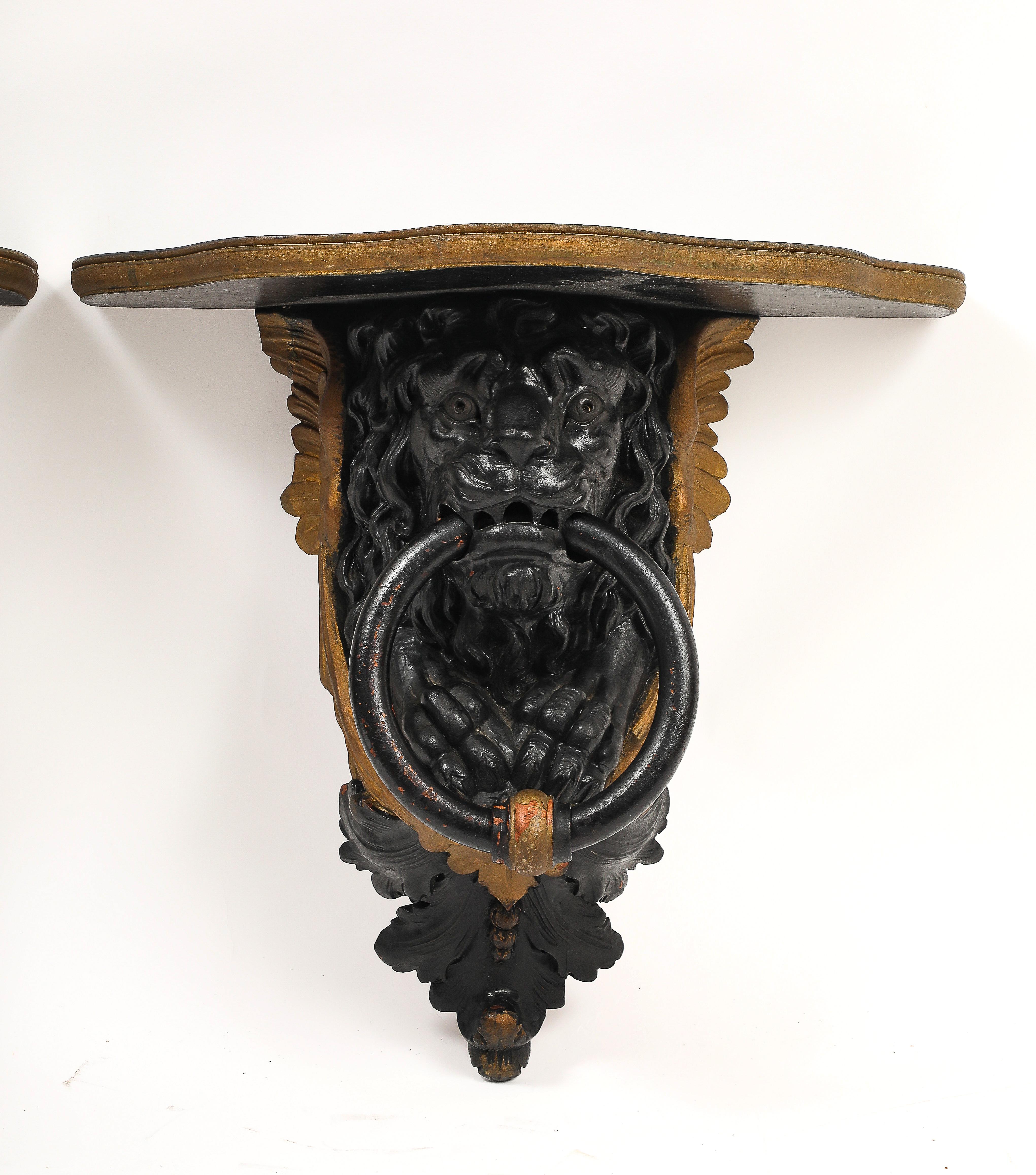 Fine XIX secolo Coppia di mensole da parete inglesi Regency in lacca nera e oro con maschere di leone e anelli in vendita