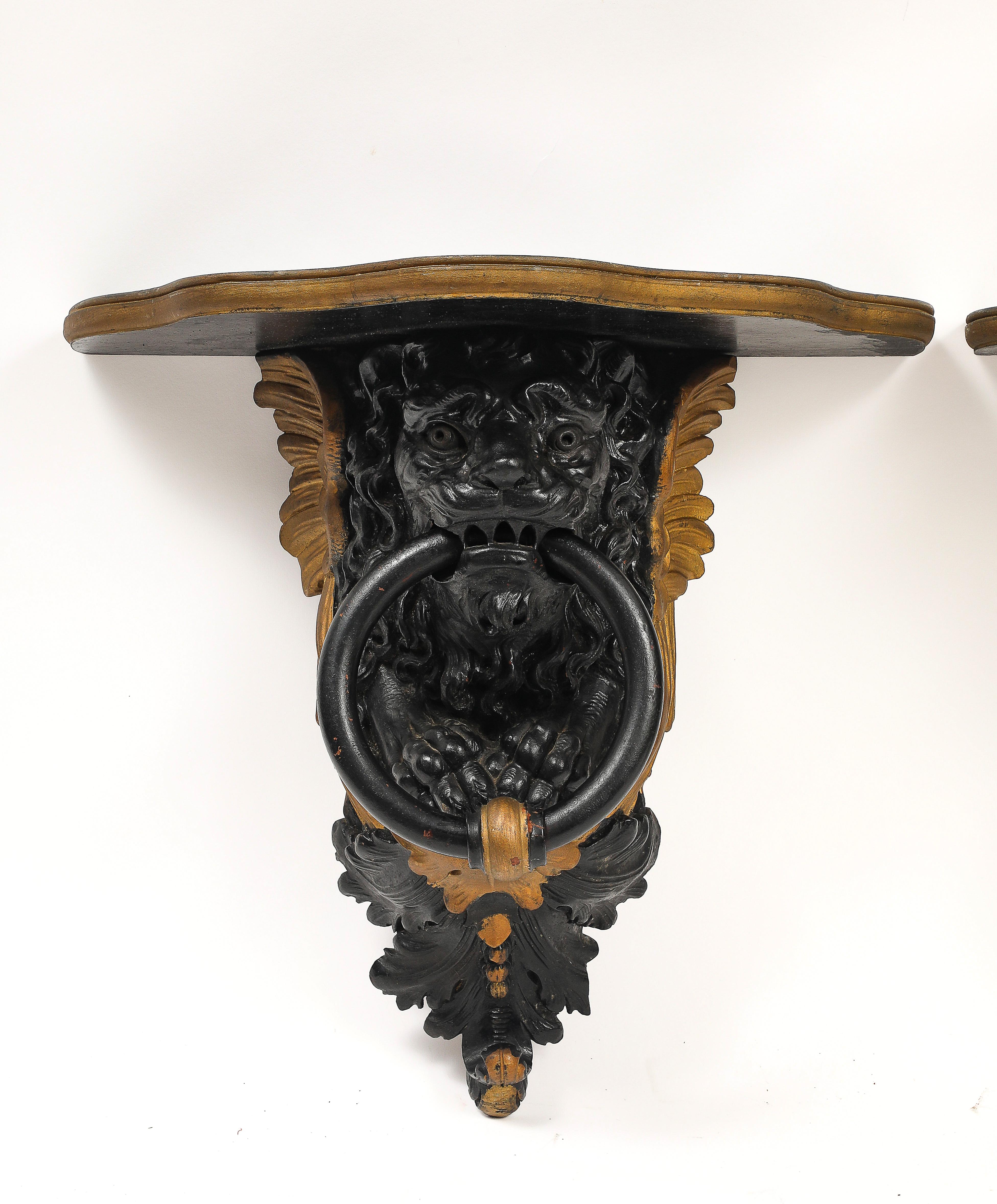 Legno Coppia di mensole da parete inglesi Regency in lacca nera e oro con maschere di leone e anelli in vendita