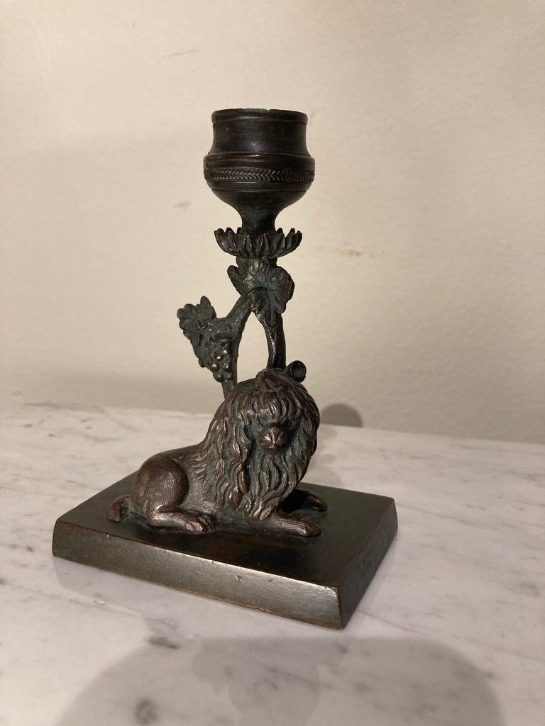 A sweet pair of early 19th century English miniature bronze candlesticks with dogs that look like lions. Presumably a male and female, the one on the left with her hair tied into a pony tail. Both with branch form candle sticks supporting the