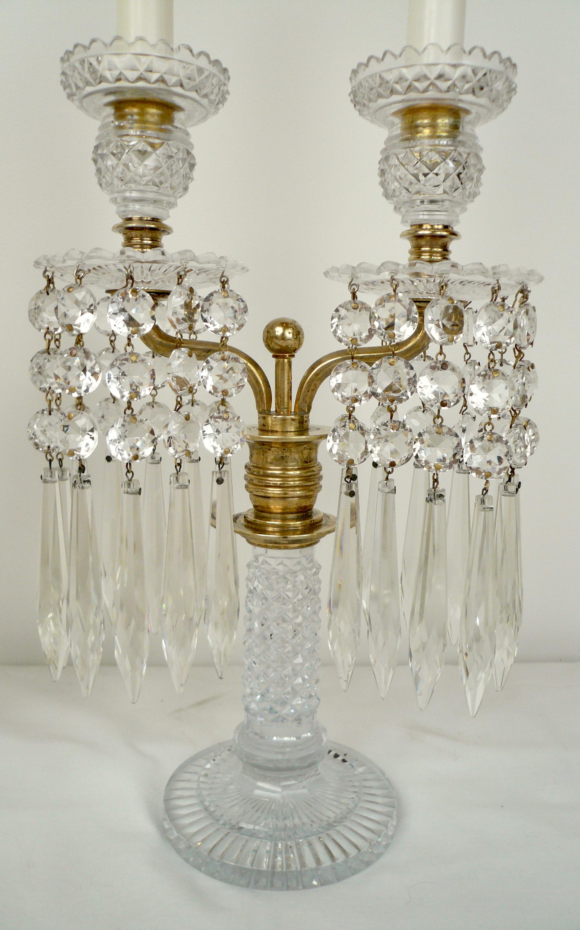 This quality pair of crystal candelabra are attributed the the famous Regency period maker John Blades. They feature radial cut bases with diamond cut shafts, and are mounted with twin bronze arms.
 