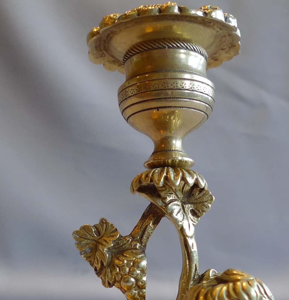 A rare and unusual true pair of naïve ormolu English Regency candlesticks. Set upon each rectangular base is a King Charles spaniel in repose. Behind the spaniel is a branch with leaves and fruit terminating in a candle sconce and original drip pan.