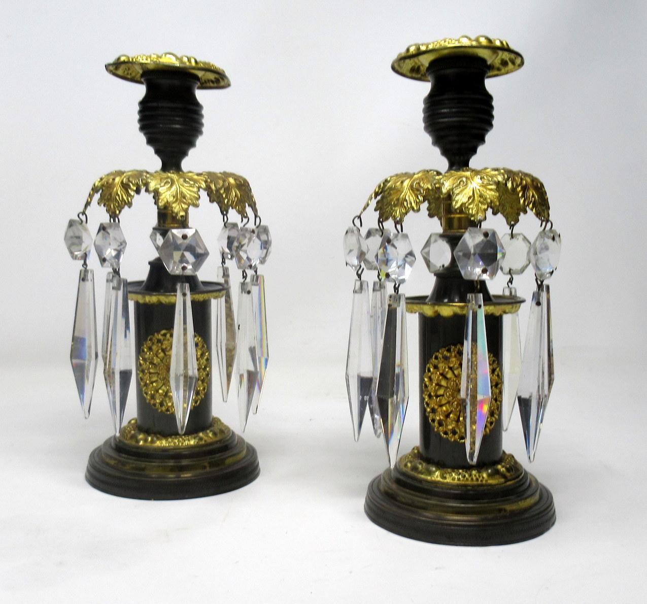 A stylish pair of English Regency Period patinated bronze and Ormolu weighted table or mantle single light Lustres, first quarter of the 19th century.

Each with bronze reeded sconces above Acanthus leaf canopies decorated with eight original hand