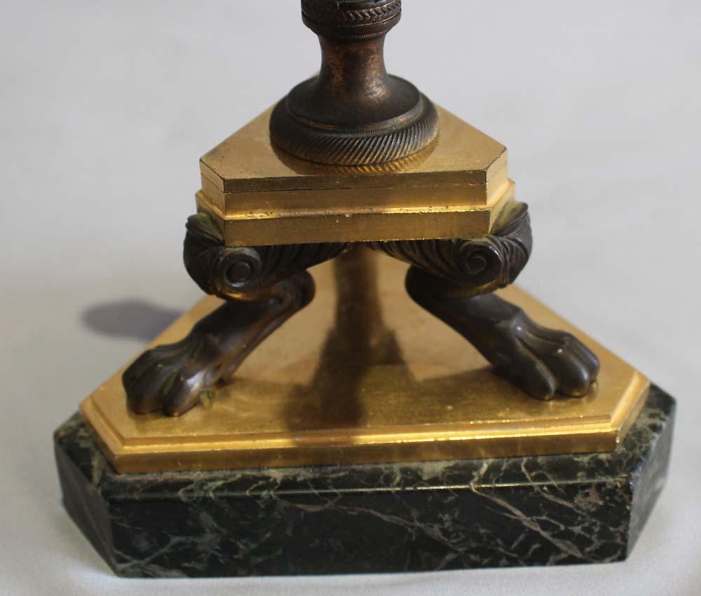 pair of English Regency triform candlesticks. Ormolu, patinated bronze and antique marble vert. Set on a green marble base the sticks sit on a triangular plate of fire gilded ormolu. Three paw footed legs in patinated bronze rise to a further ormolu