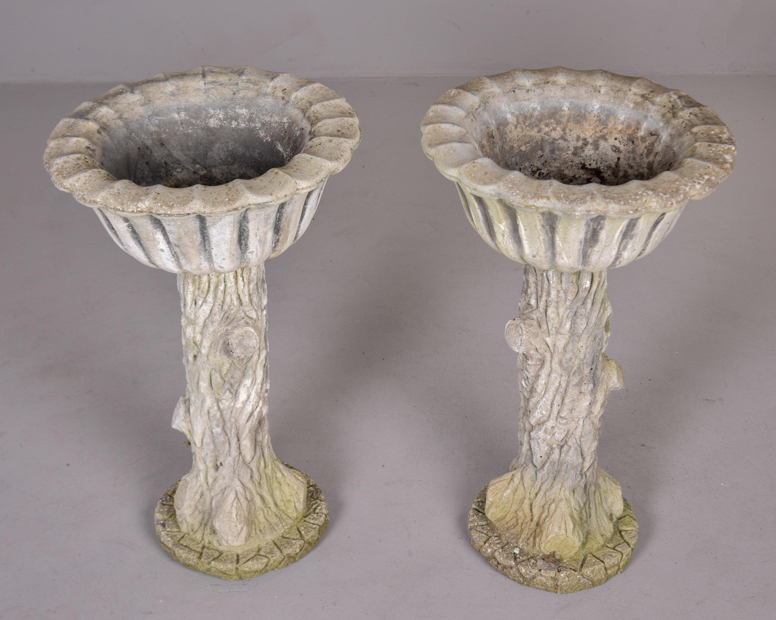 Found in England, this pair of garden planters date from the 1980s. Made of cast stone / cement, these planters have a tree trunk-form base topped with a fluted planting bowl. Tops are removable for moving / shipping. Some age-related moss/patina.