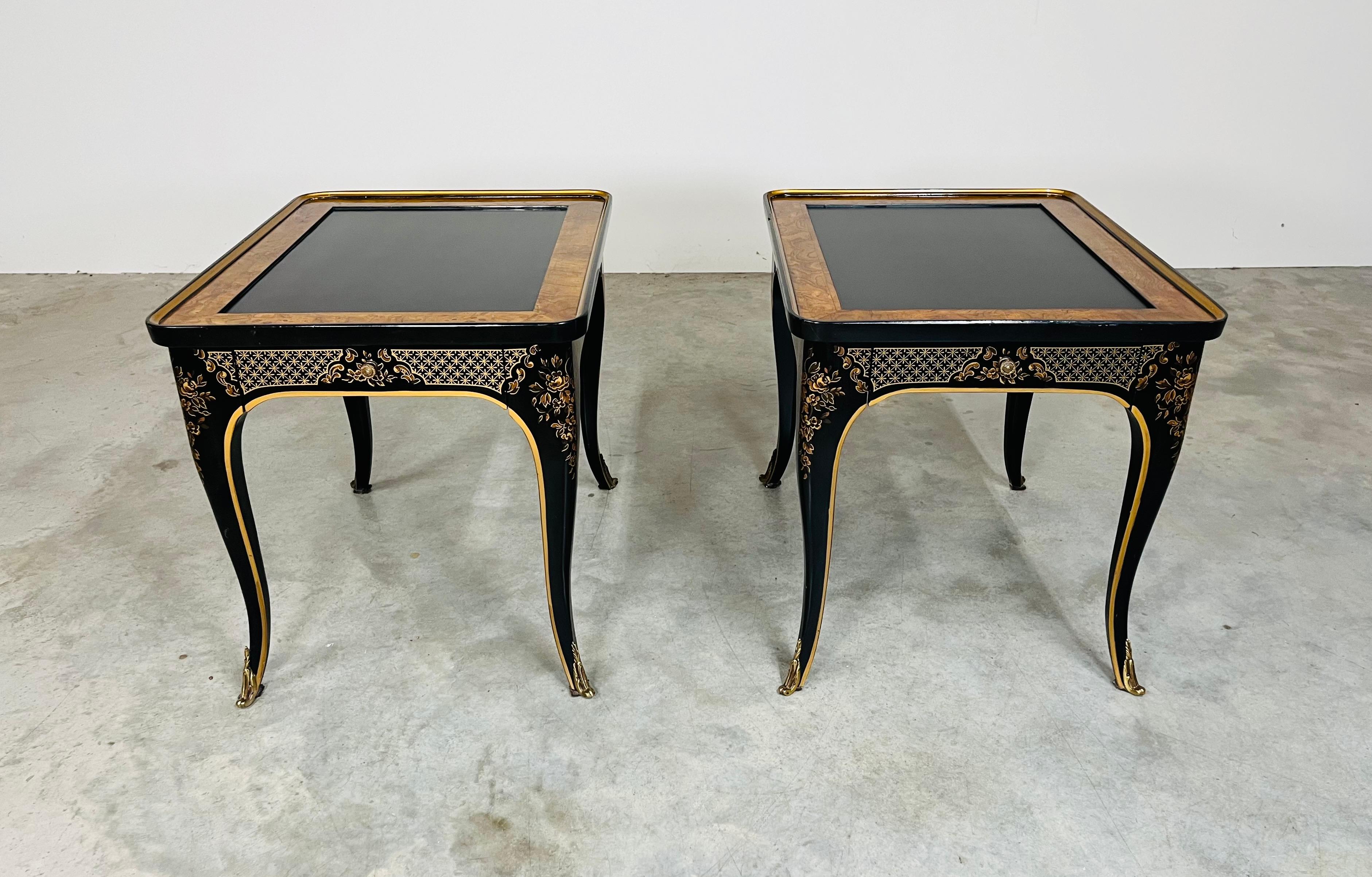 A striking pair of elegant ‘Et Cetera’ single drawer side tables in the Chinoiserie style having black lacquer tops and frames that feature hand painted gold details throughout. The tops are framed with beautiful olive Burlwood adding an opulent