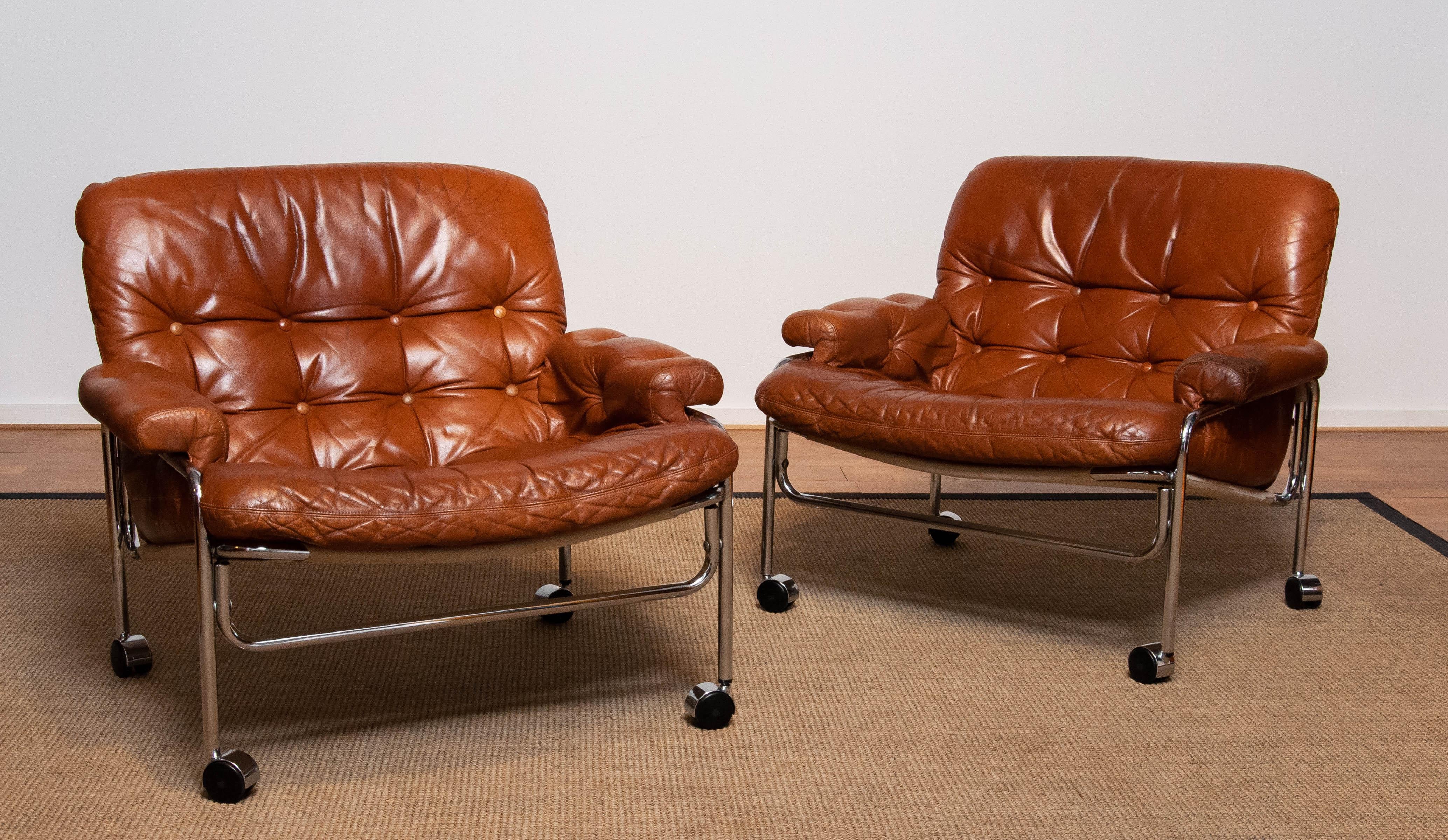 Beautiful pair lounge / easy chairs in aged brown / tan leather with great patina and tubular chrome metal tubular frames designed by Pethrus Lindlöfs for A.B. Lindlöfs Möbler Lammhult, Sweden. Model Eva.
The aged leather gives these chairs the