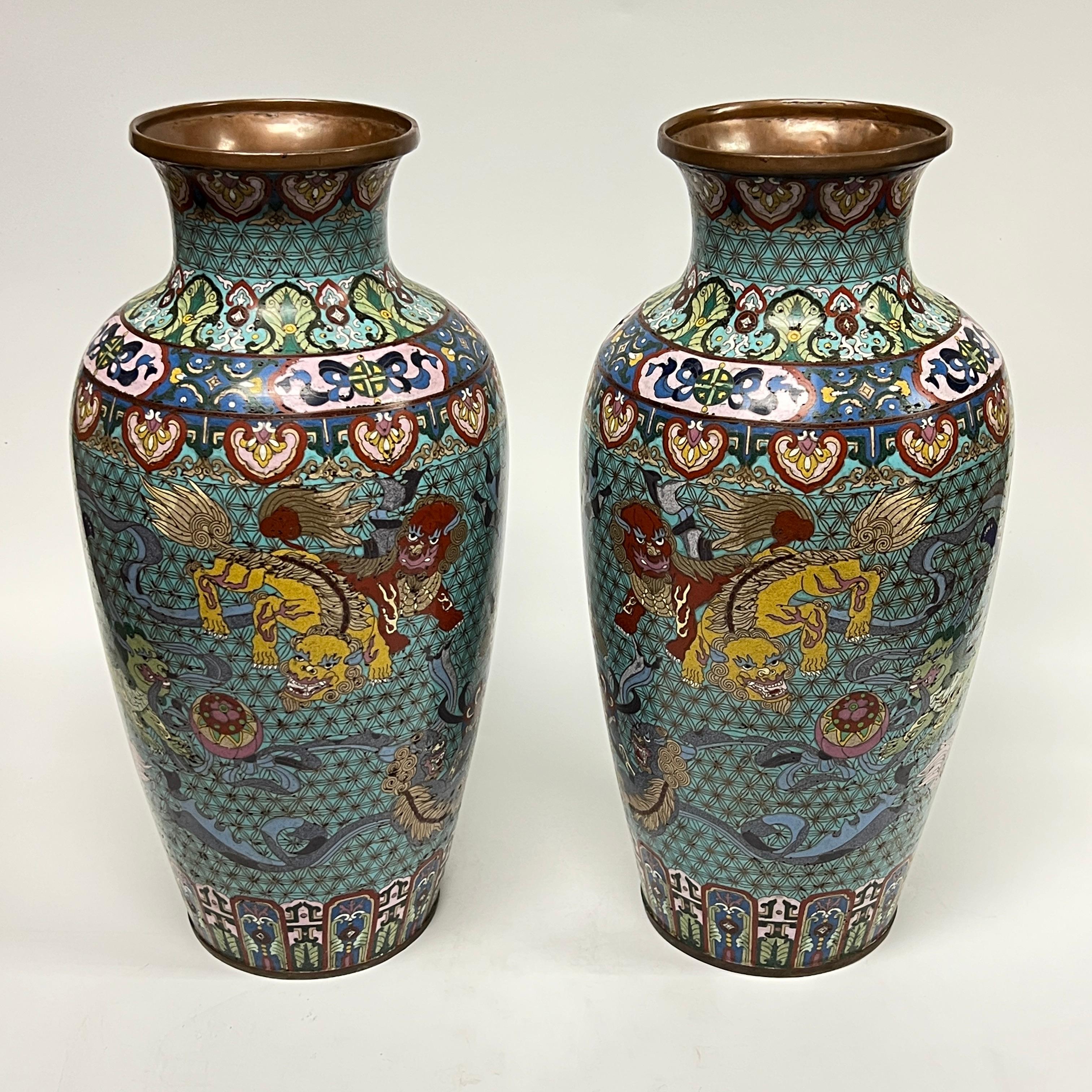 Coppia di eccezionali vasi antichi (fine XIX secolo) in metallo giapponese del periodo Meiji con raffinati disegni smaltati a cloisonne di leoni guardiani e draghi.  Ciascuna è alta 20 1/4 di pollice e ha un diametro di 9 pollici.