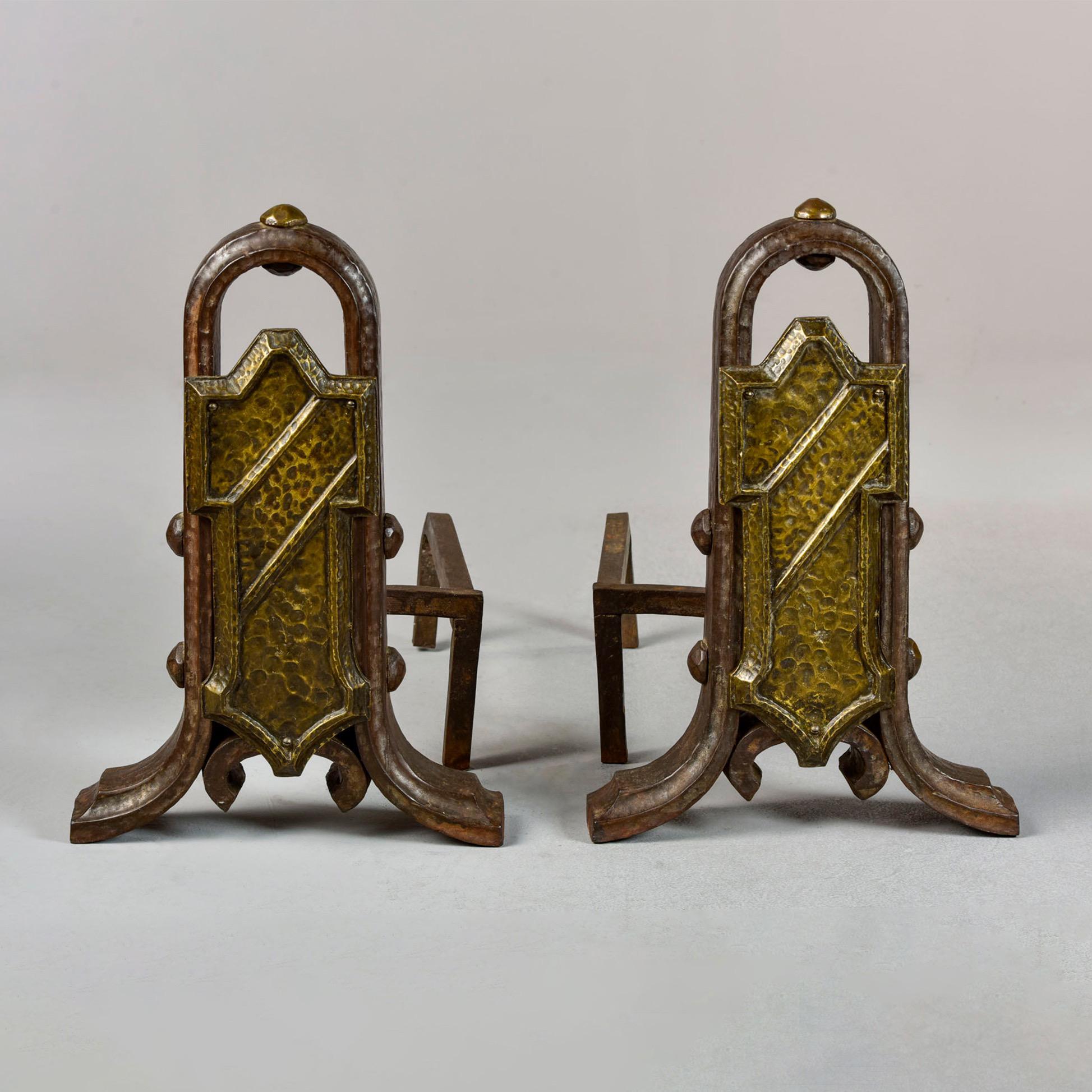 Circa 1910 pair of extra large andirons with plenty of Arts & Crafts era style in the hammered iron and brass fronts. Original firedogs. Unknown maker. Found in the US. Sold and priced as a pair.