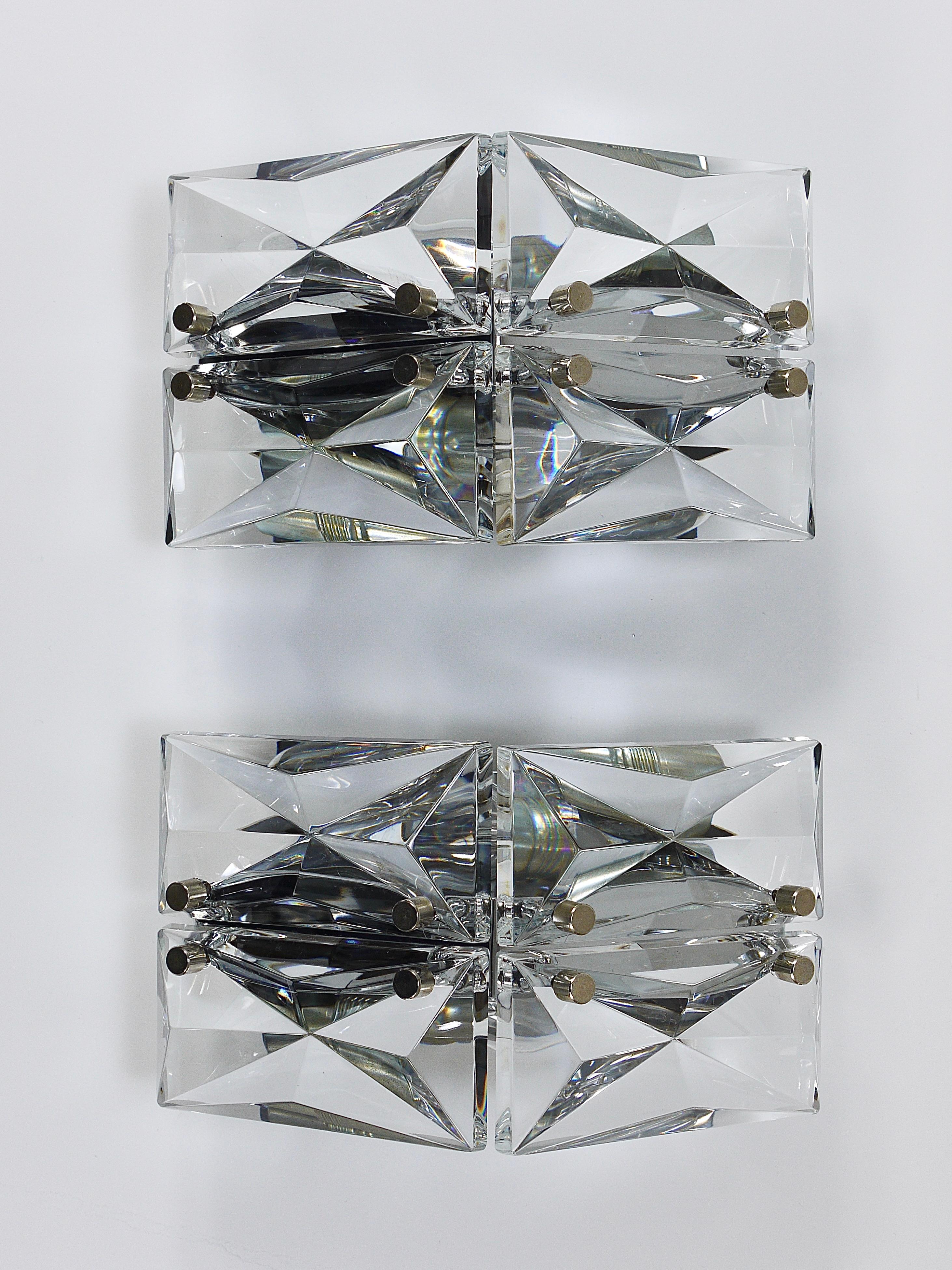 Un par de exquisitos apliques triangulares de mediados de siglo de la década de 1970, fabricados con gran calidad por Kinkeldey en Alemania. Cada candelabro presenta herrajes de latón cromado adornados con cuatro paneles de cristal facetado que