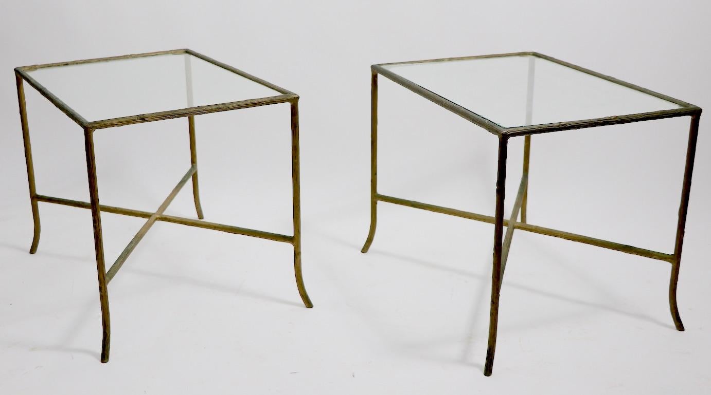 Chic pair of metal and glass end, or side tables having textured cast metal frames which have twig like surfaces. The faux wood ( iron ) frames are in later gilt brass paint finish. Both have their original glass tops, tops show inconsequential wear