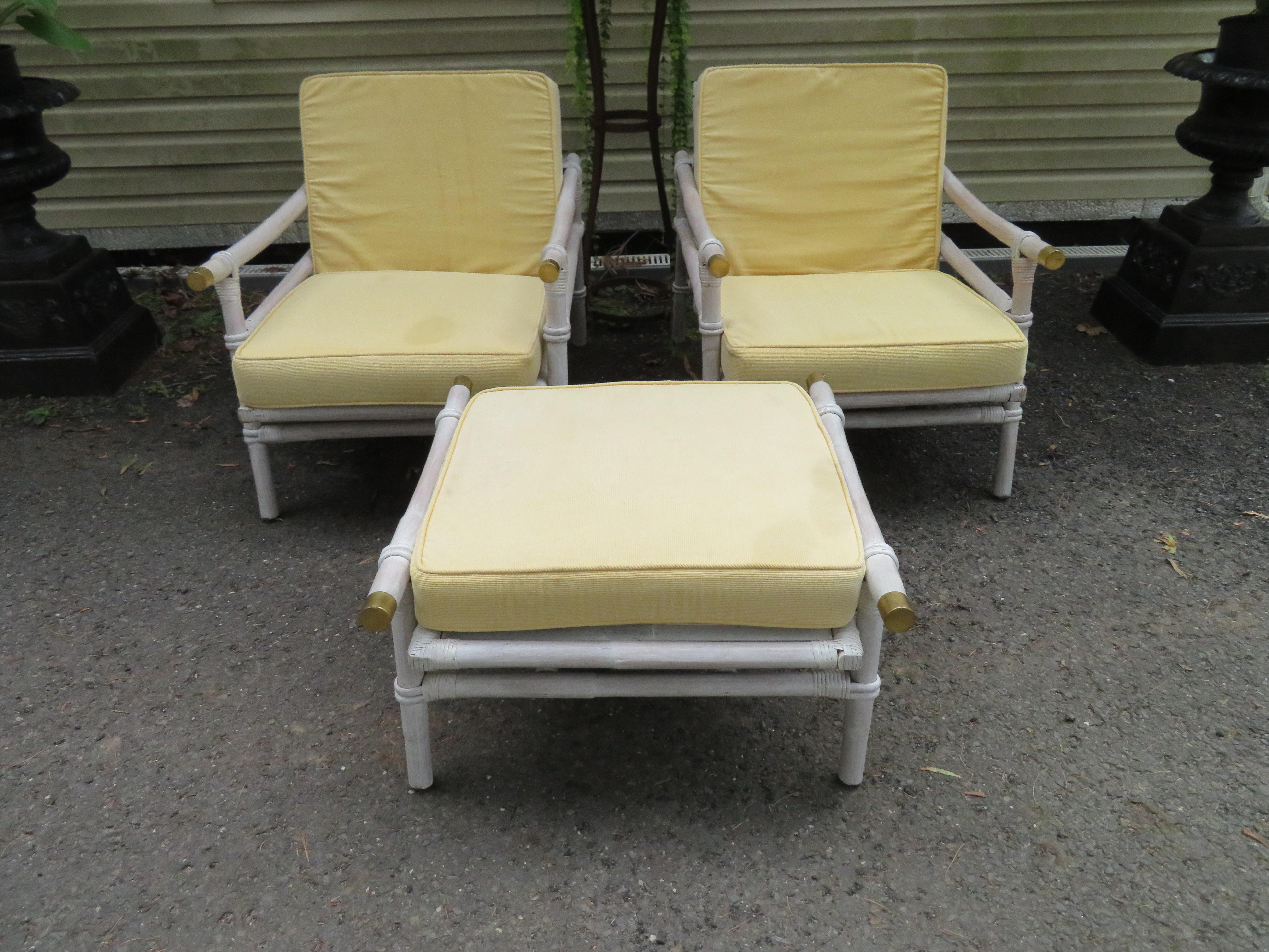 Lovely pair Ficks Reed rattan Campaign style lounge or club chairs plus one ottoman with interesting brass cap accents by John Wisner for the Far Horizons collection, 1954. This pair retains their original very rare white washed finish in nice