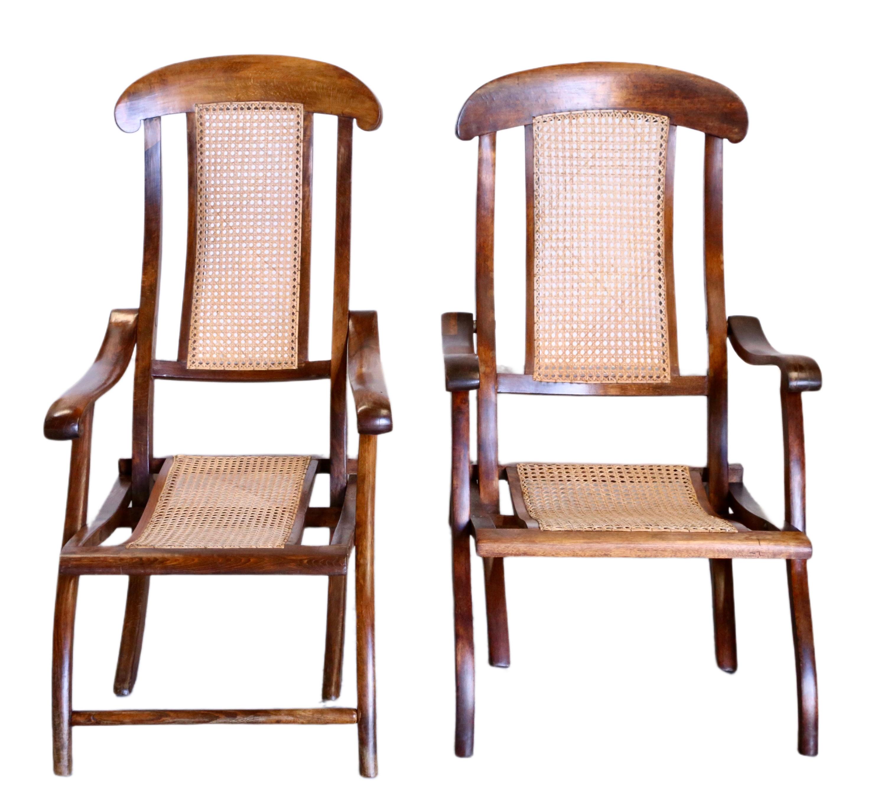 Step back in time to the adventurous era of the Victorian age with these exquisite folding steamer chairs - slightly different size, crafted from solid walnut and adorned with woven cane. These chairs, reminiscent of the grand voyages undertaken by