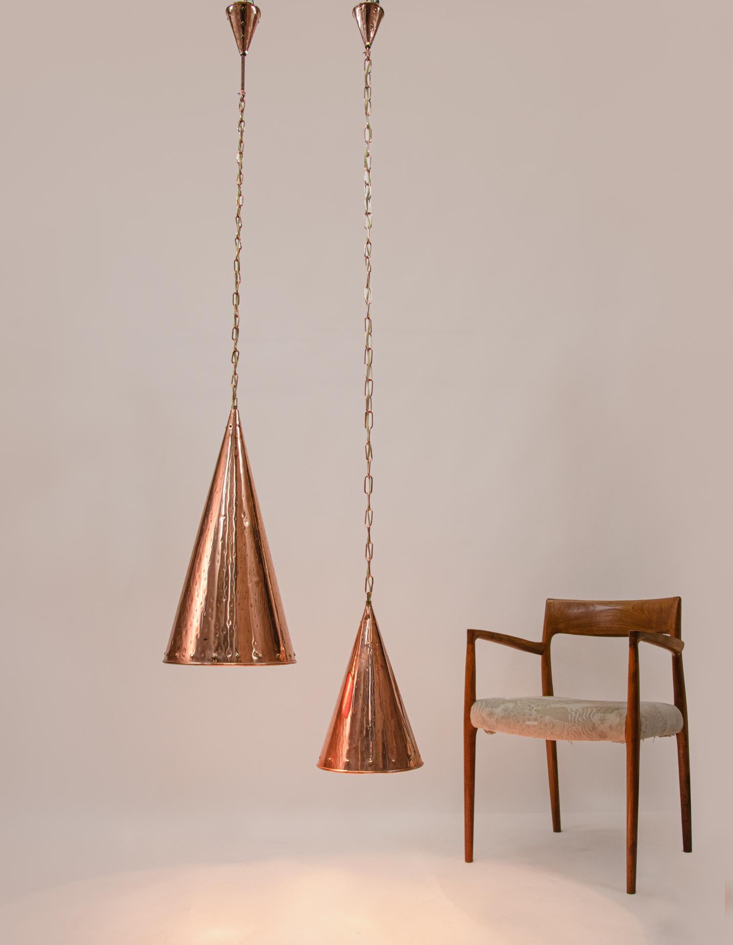 Elegant pair of Danish hand-hammered copper cone pendant lamps hanging on long chains. 

Design / Manufacturer: E.S Horn Aalestrup. 
Made in Denmark early 20th century. 
Larger cone: H 24.8