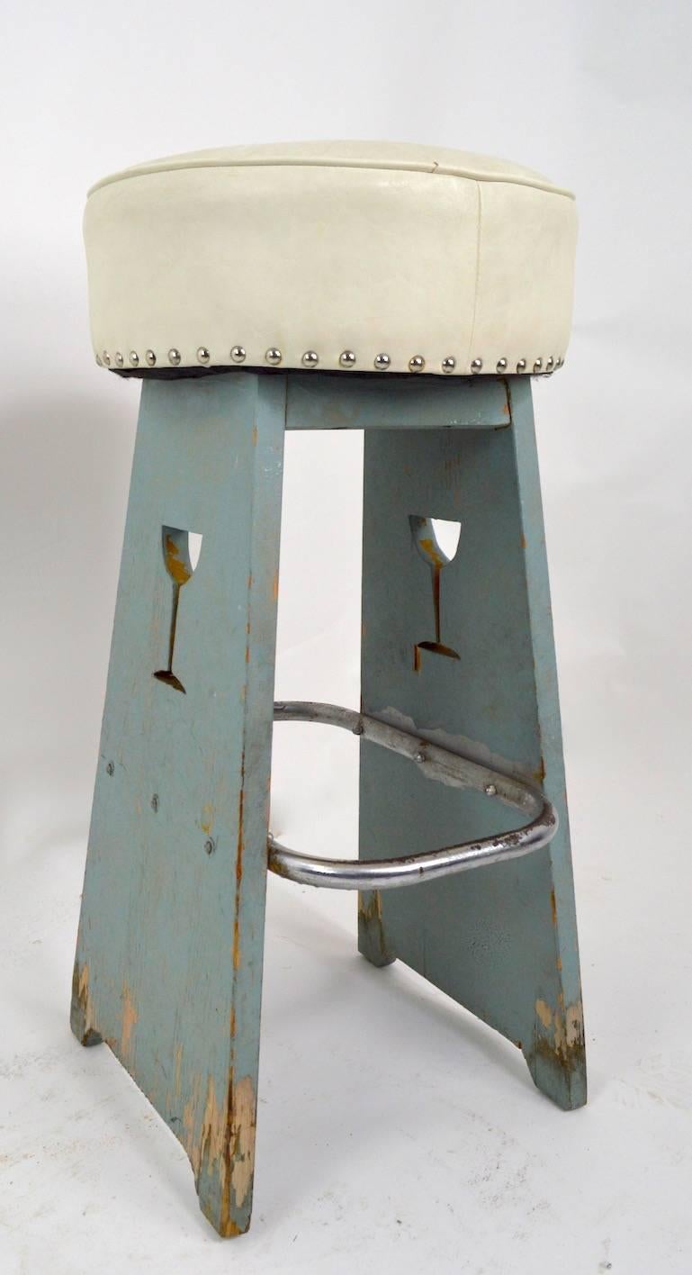 Pair of Art Deco stools with martini glass cut outs. Folky style, chic stools from the period. Both show cosmetic wear, paint loss, wear to chrome foot rail etc. Diameter of upholstered top 15 inches x 5.5. Foot rail 12 inches H off floor.