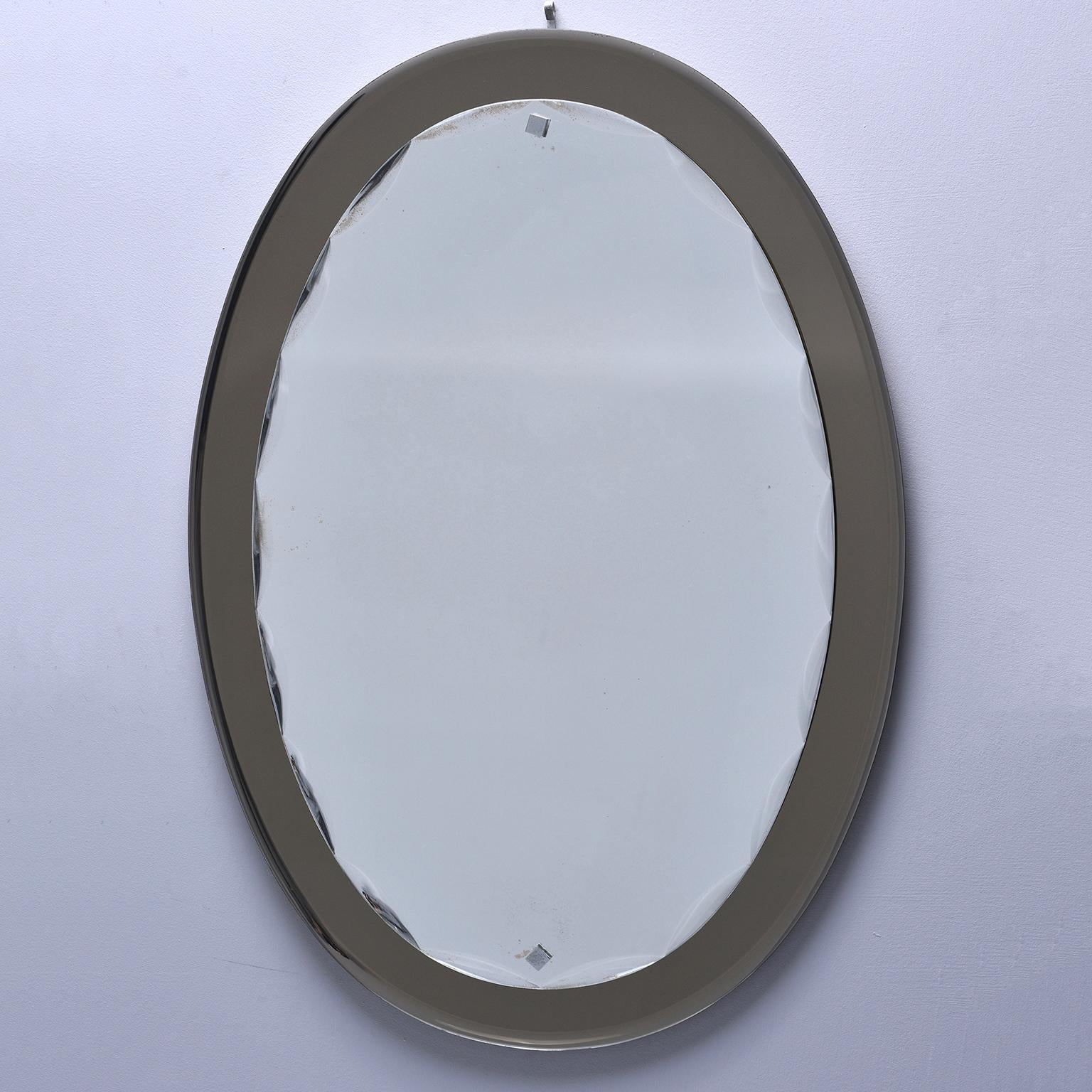Pair of Fontana Arte oval mirrors have taupe glass base with overlay mirror with beveled and scalloped edge, circa 1960s. Sold and priced as a pair.