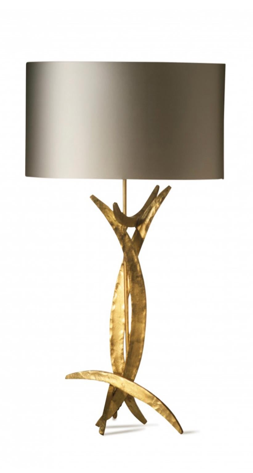 This pair of steel forged table lamps has a raw shape with its metal parts in bright gold finish or burnished one. In the photo is visible the bright one.
The contrast is stronger with the presence of the silk oval lamp shade. This Brutalist style