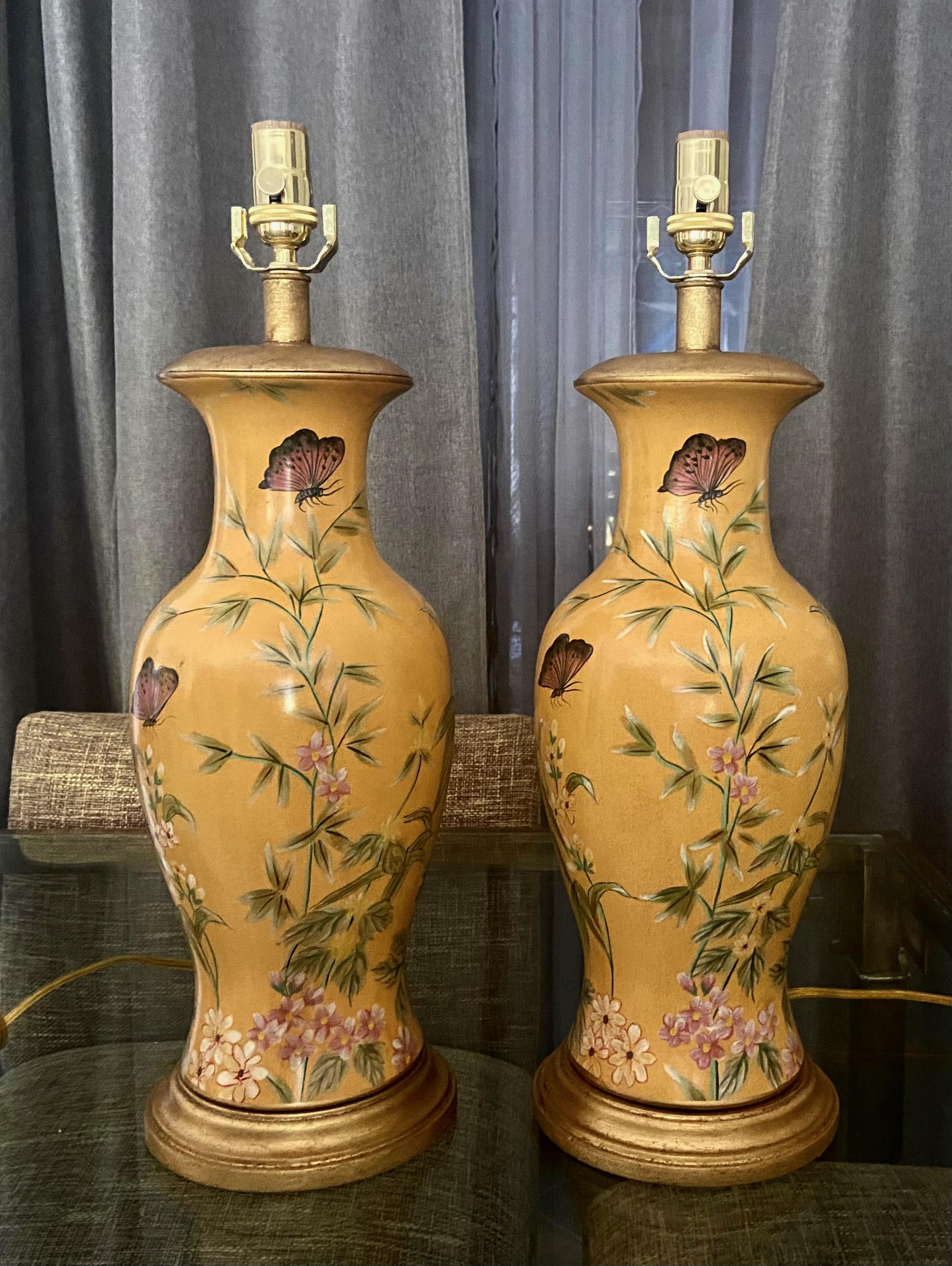 Pair of muster yellow baluster form ceramic table lamps with giltwood bases and vase caps. Nicely decorated with painted butterfly and bamboo leaf motif. Produced by Frederick Cooper. New 3 way brass sockets.
 