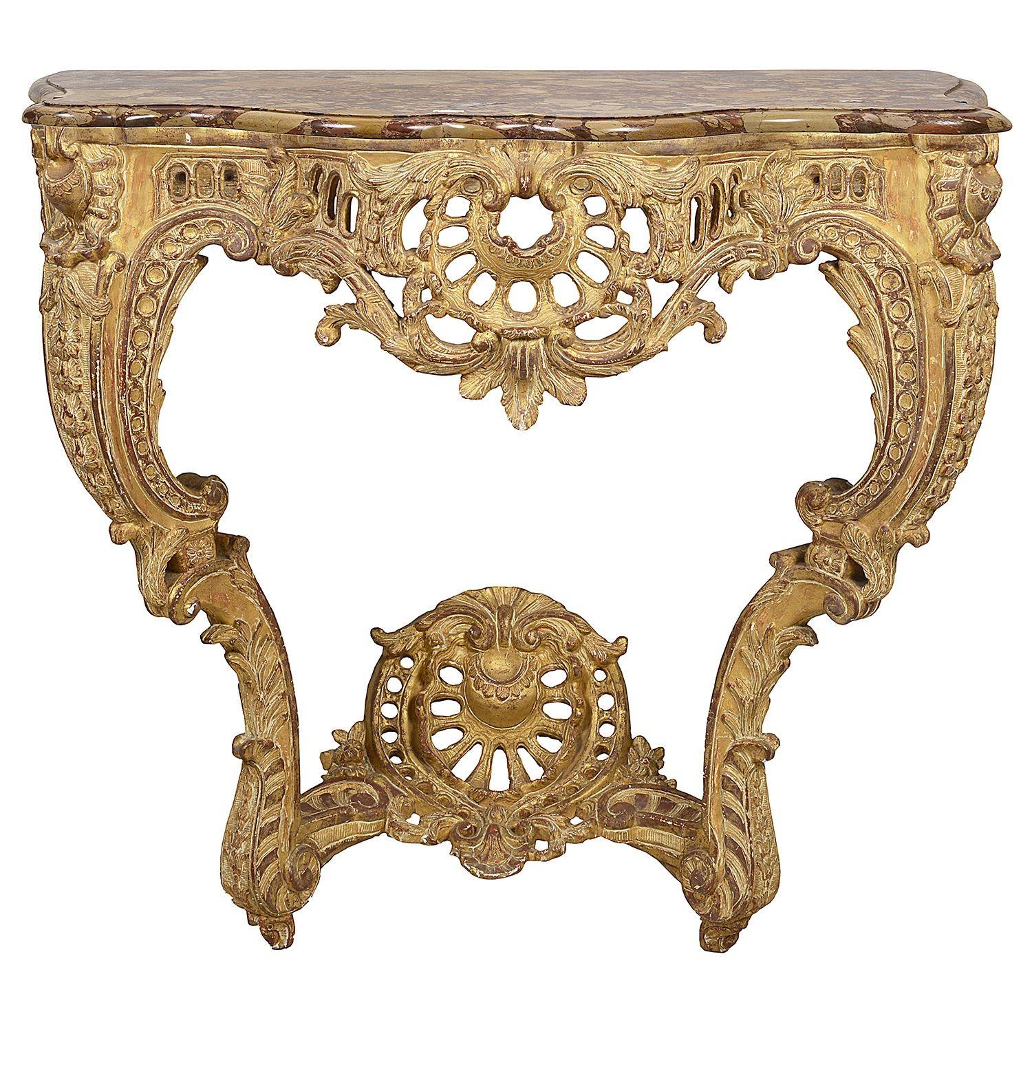 A very impressive pair of french 18th Century carved gilt wood console tables, each with their original Breccia marble tops. Wonderful scrolling rococo influenced foliate decoration with pierced fretwork, raised to the frieze and raised on carved