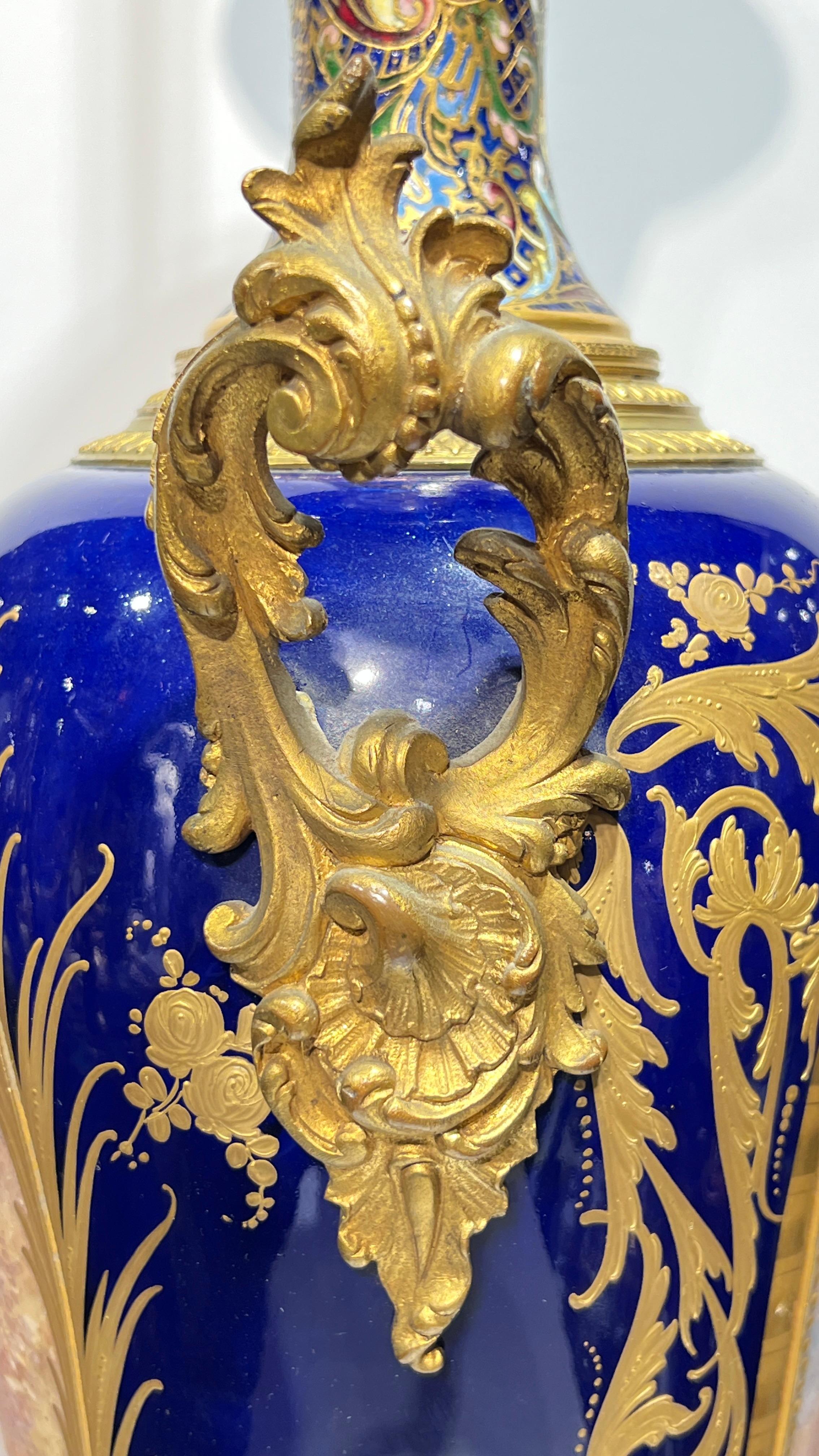 Coppia di imponenti vasi antichi (XIX secolo) in porcellana francese con montature in bronzo intarsiate in smalto dorato e champleve, con fondo smaltato blu cobalto, ampie decorazioni dorate e grandi cartigli raffiguranti cupido e cherubini accanto