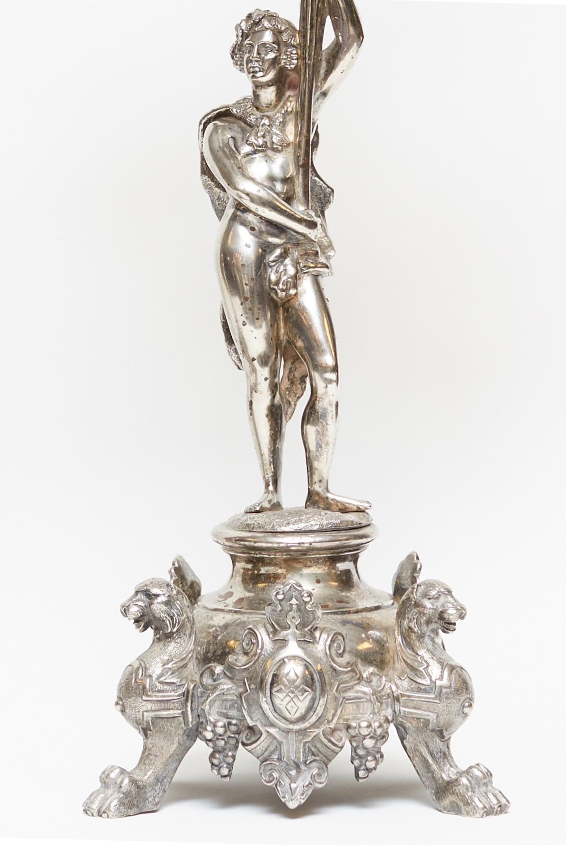 Pair of French 19th century silvered bronze candelabras with neoclassical figures holding foliate style branch of candle arms, standing on three-legged pedestals with griffins and shields.