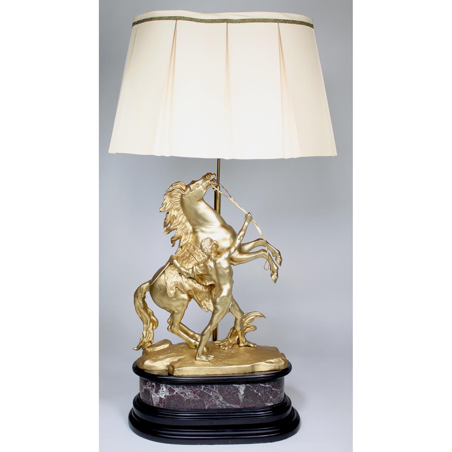 Paire de sculptures en bronze doré du 19e/20e siècle représentant les chevaux de Marli (aujourd'hui transformées en lampes), d'après l'original de Guillaume Coustou (français, 1677-1746). La grande paire de sculptures équestres en bronze, patinées à