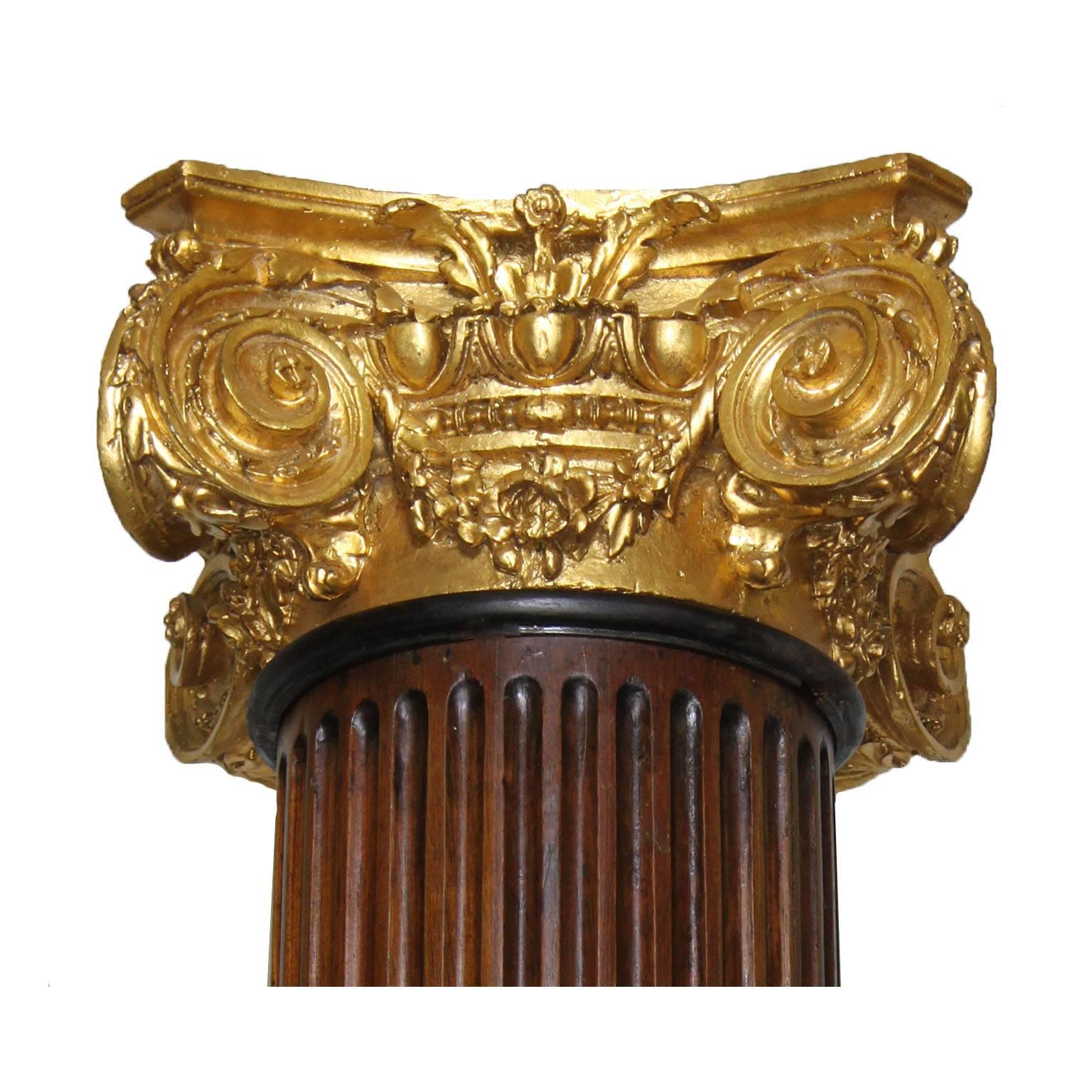 A large pair of French 19th-20th century Louis XVI style carved walnut and gilt-cast Gesso Architectural Corinthian columns. The slender carved walnut column resting on a square plinth and crowned with a gilt-carved cast gesso capital decorated with