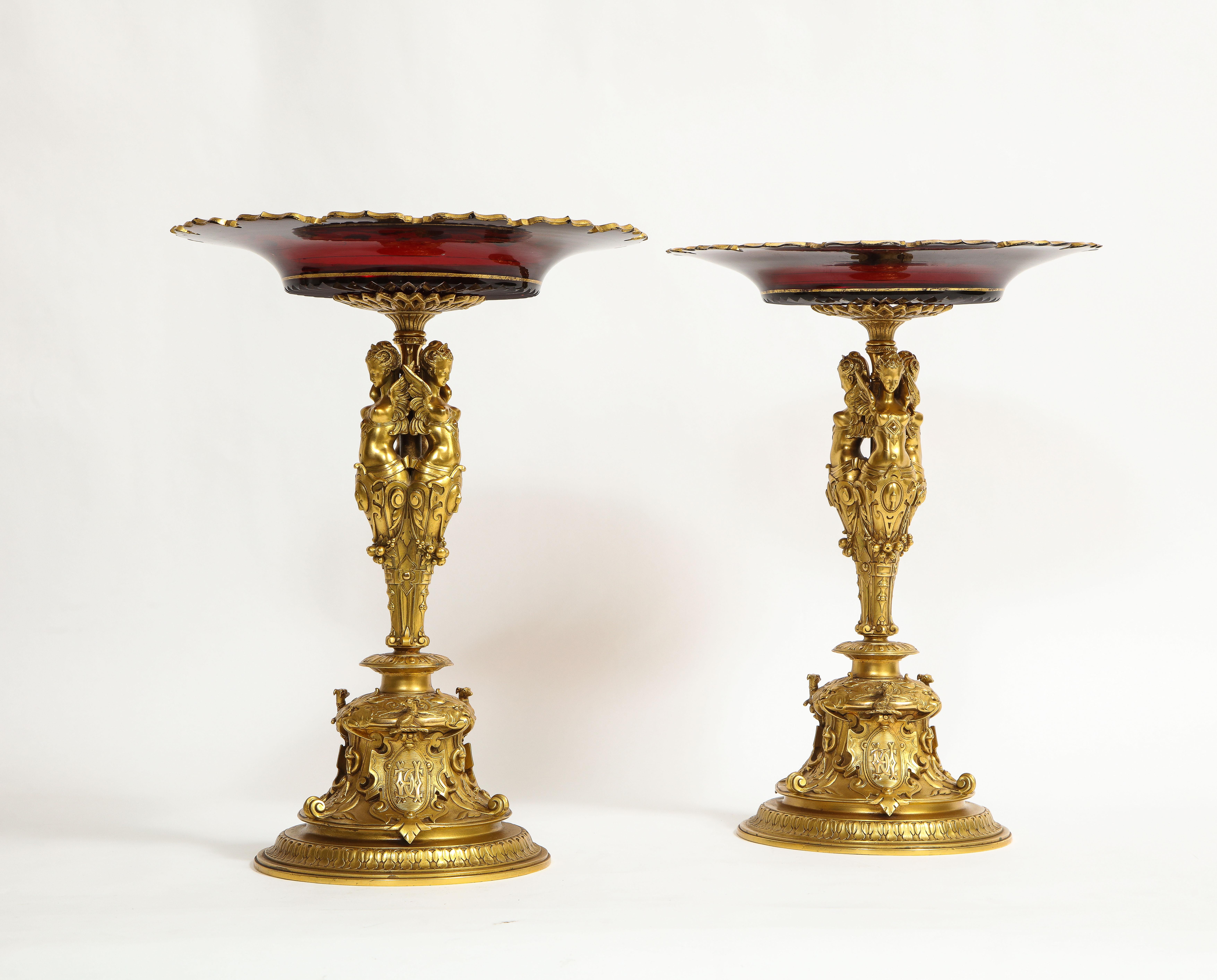 An impressive pair of French 19th century Louis XVI style red Baccarat crystal ormolu mounted tazzas/centerpieces. The red glass tops are each beautifully hand-carved and hand-detailed with 24K gilt decoration depicting leaves, vines and a star