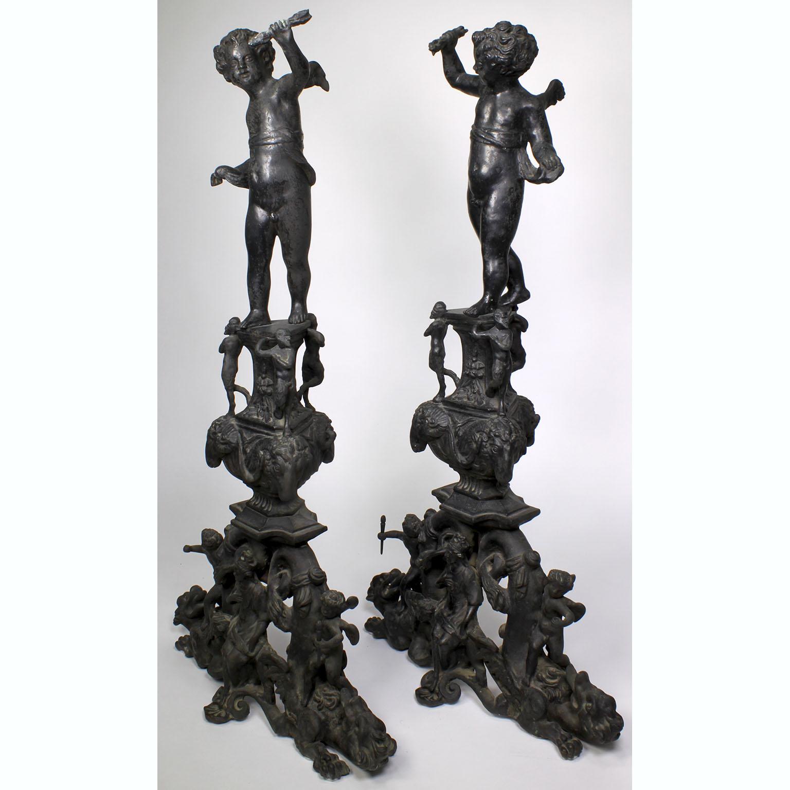 Paire de chenets (andirons) français de style baroque, datant du 19e-20e siècle, en bronze patiné. Chaque chenet est surmonté d'un chérubin debout sur un support flanqué de styrs et de têtes de chèvres royales, au-dessus d'une plinthe à volutes