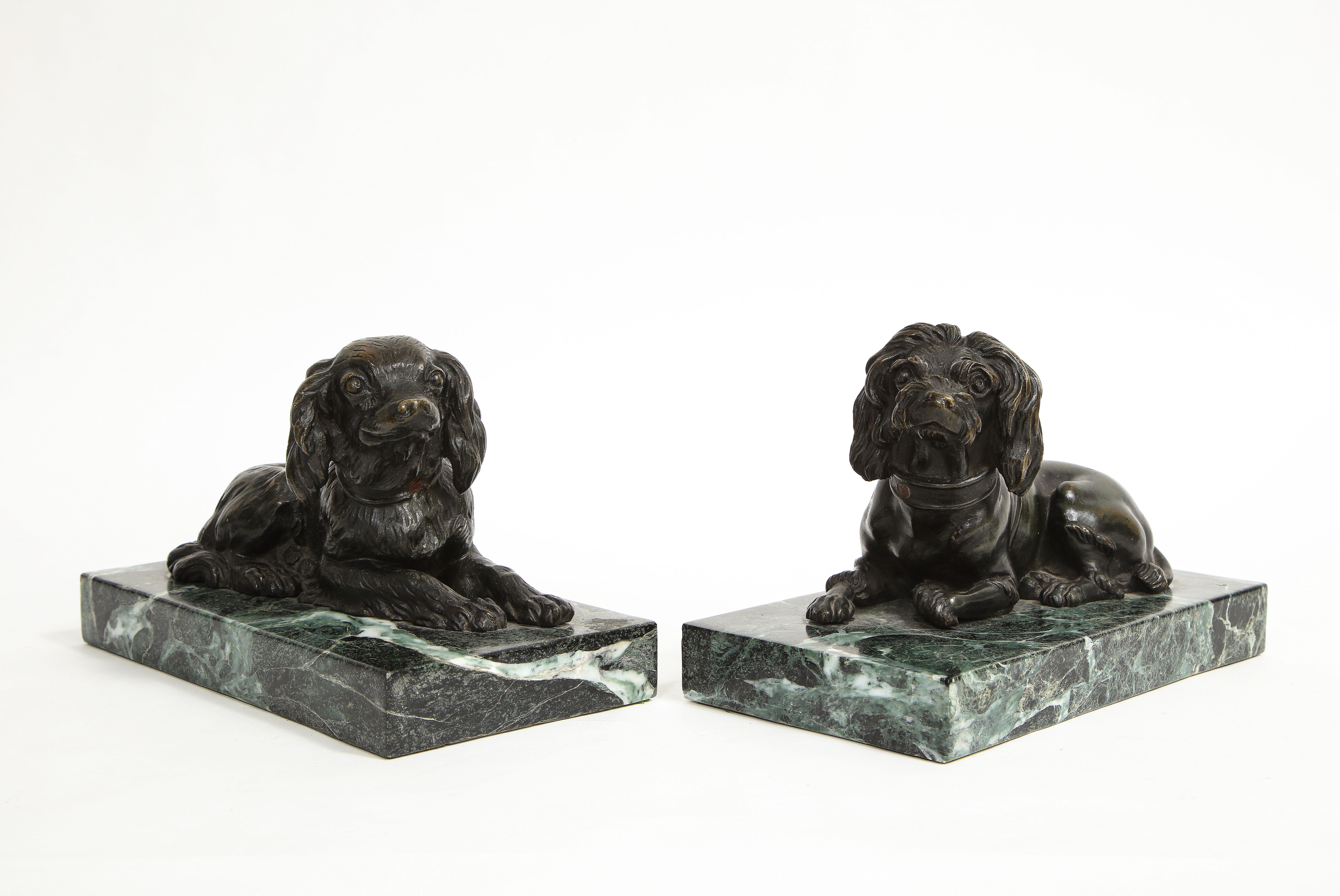 A Beautiful Pair of Italian 19th Century Grand Tour Patinated Bronze Dogs on Green Marble Bases. Each dog is beautifully cast, hand-chassed, and hand-chiseled. They are life-like in appearance, each with flowing fur and delicate smiles. They are