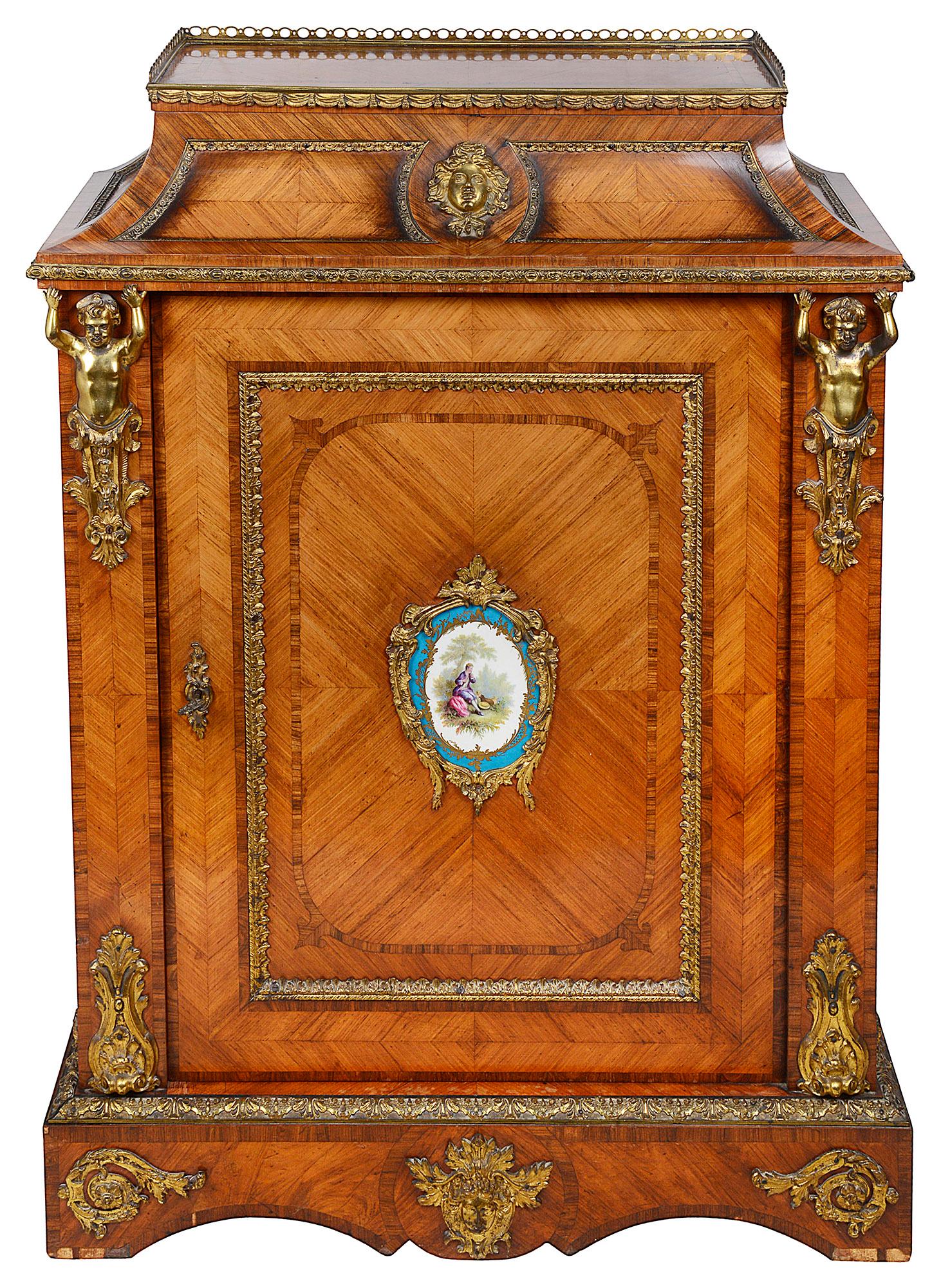 A very good quality pair of 19th century French ormolu and porcelain mounted pier cabinets, each with cross-banded decoration, monopodia supports, the Sevres style porcelain plaques depicting romantic scenes, mounted on doors that open to reveal a
