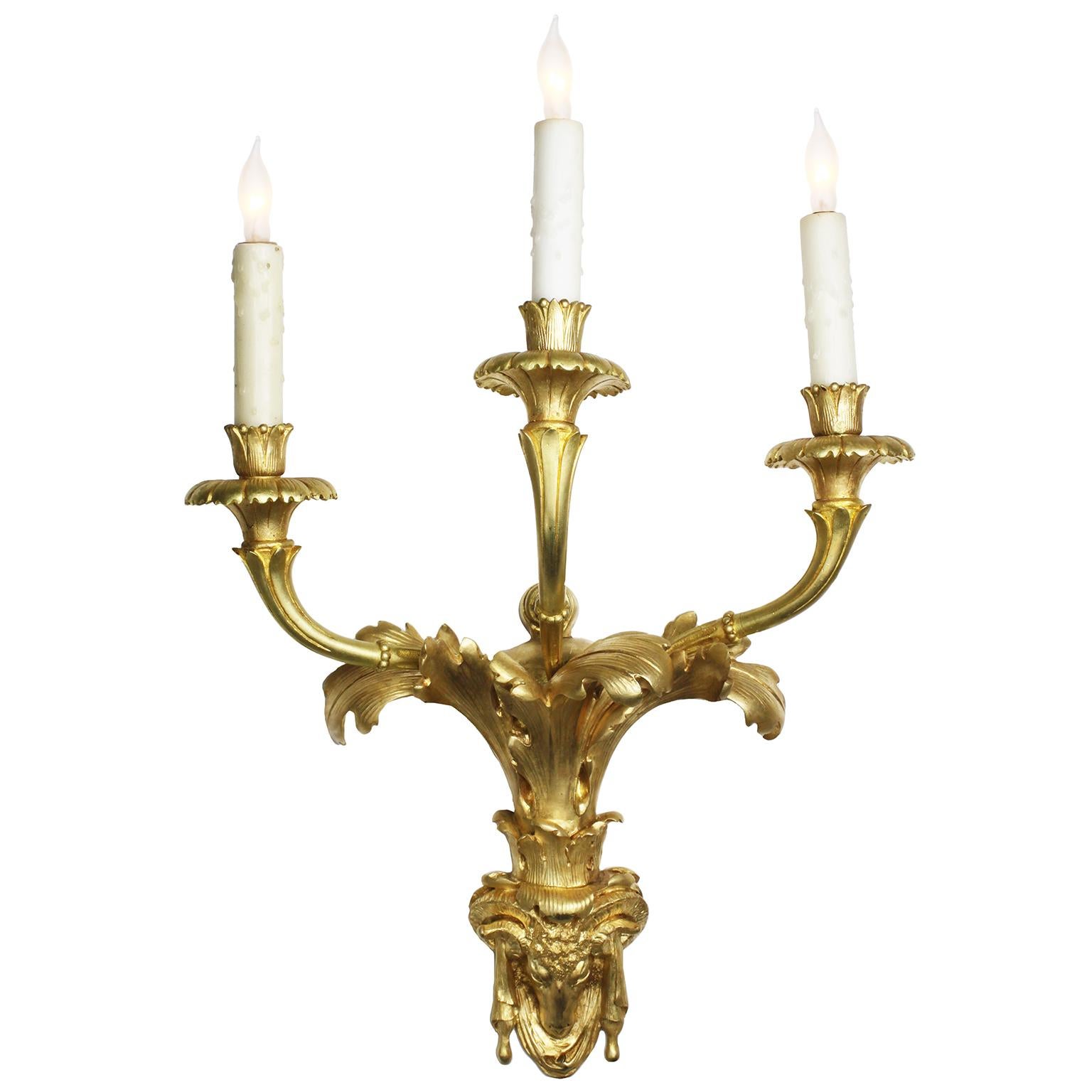 A Fine Pair of French 19th century Régence (Regency) style three-light gilt-bronze wall lights. The scrolled three light candle-lights, now electrified, above an acanthus leaf design ending with a draped ram-head finial. Circa: Paris,