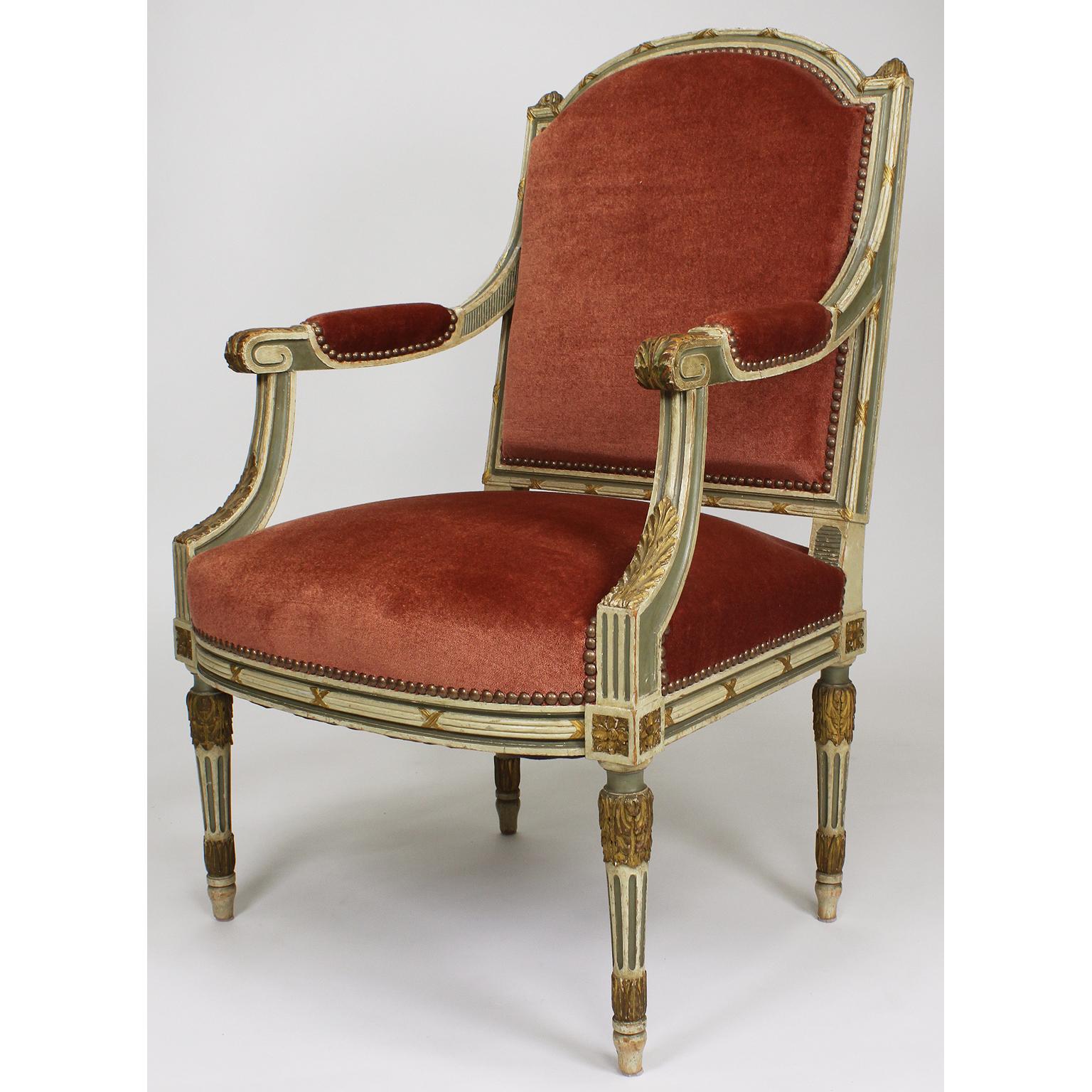 A fine pair of French 19th-20th century Louis XVI style two-tone cream and green painted with parcel-giltwood carved fauteuils armchairs. The intricately carved wood frames with a padded backrest, open scrolled and padded armrests, with