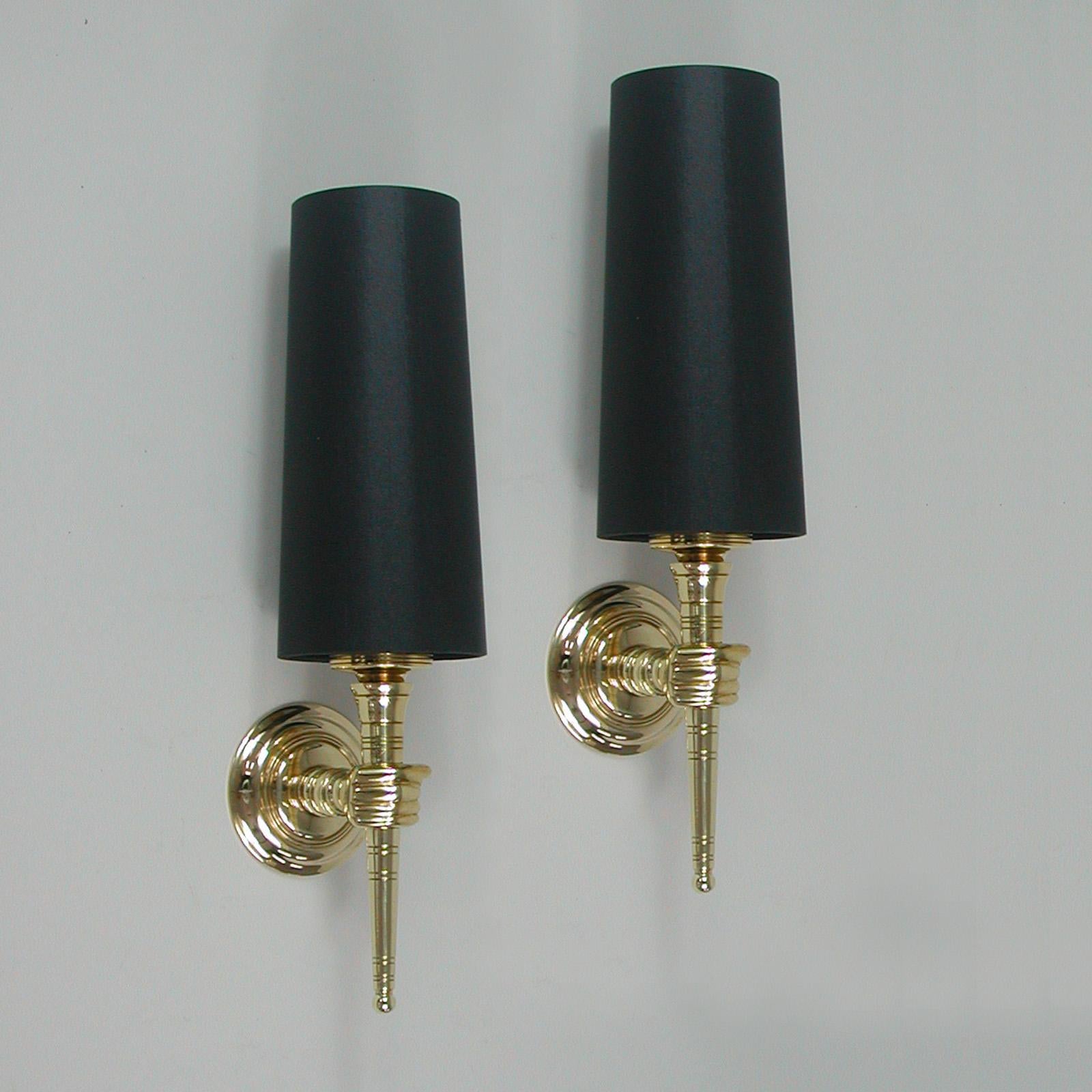 These unusual vintage sconces were designed and manufactured in France in the 1950s. They feature brass torchiere lights with (new) hand made black cotton fabric lamp shades.

Wired for use in US, Europe and Asia the lights require one E14 bulb up