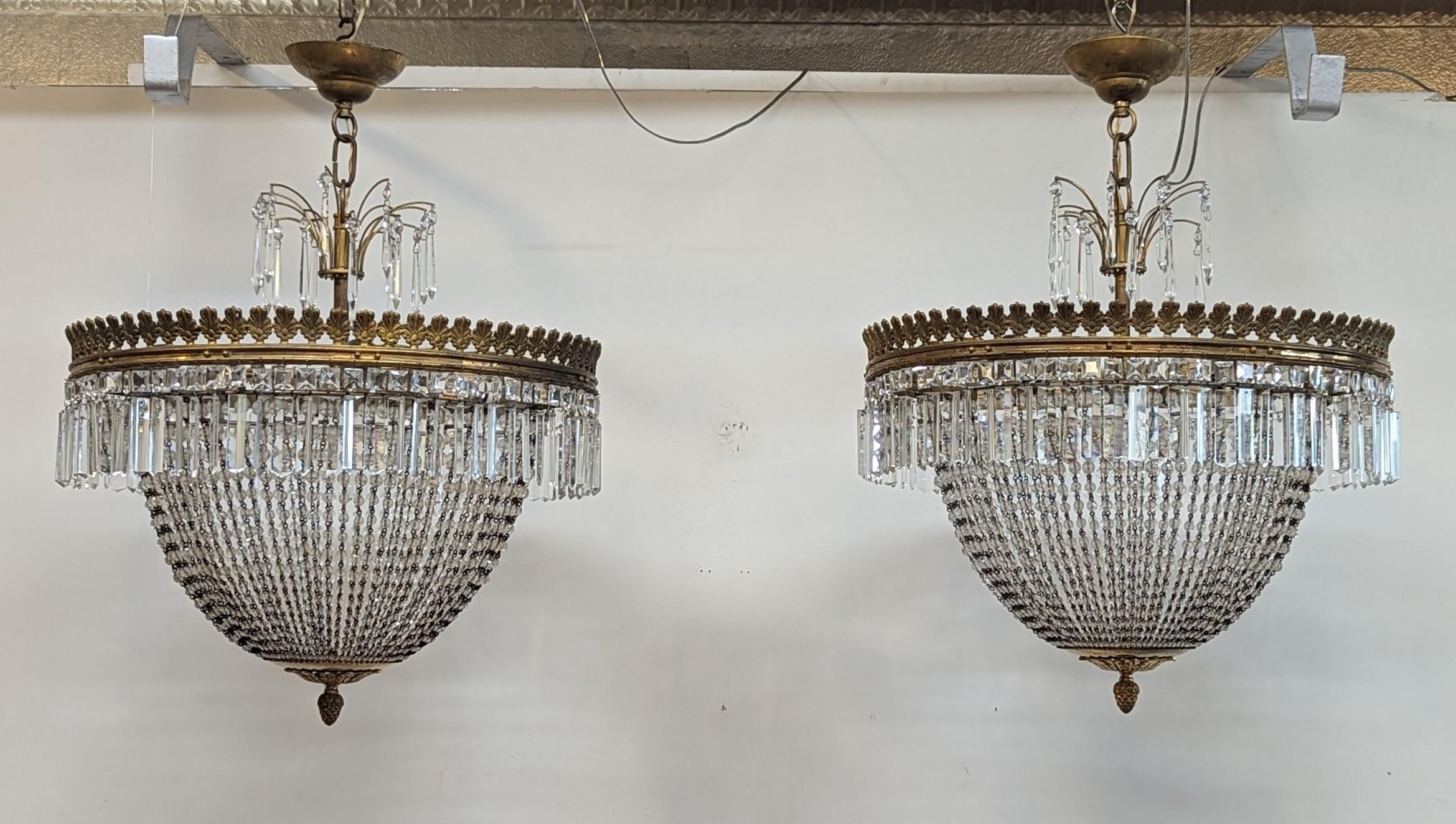 Spectacular pair of Antique French Crystal and Gilt Bronze Chandeliers.  
A matched pair of early 20th century French Basket Chandeliers.  1920's French Empire inspired Crystal and Gilt Bronze Chandeliers.  Draped graduated facet cut crystal beads