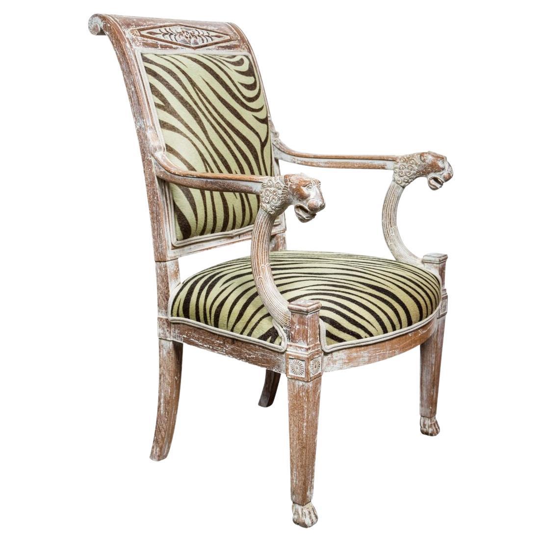 Paire de fauteuils sculptés, finition décapée. La paire de chaises présente des têtes de lion à l'avant des bras, des pieds cannelés et un dossier à volutes. Ils sont nouvellement tapissés en cuir de vachette teintée Edelman. 
