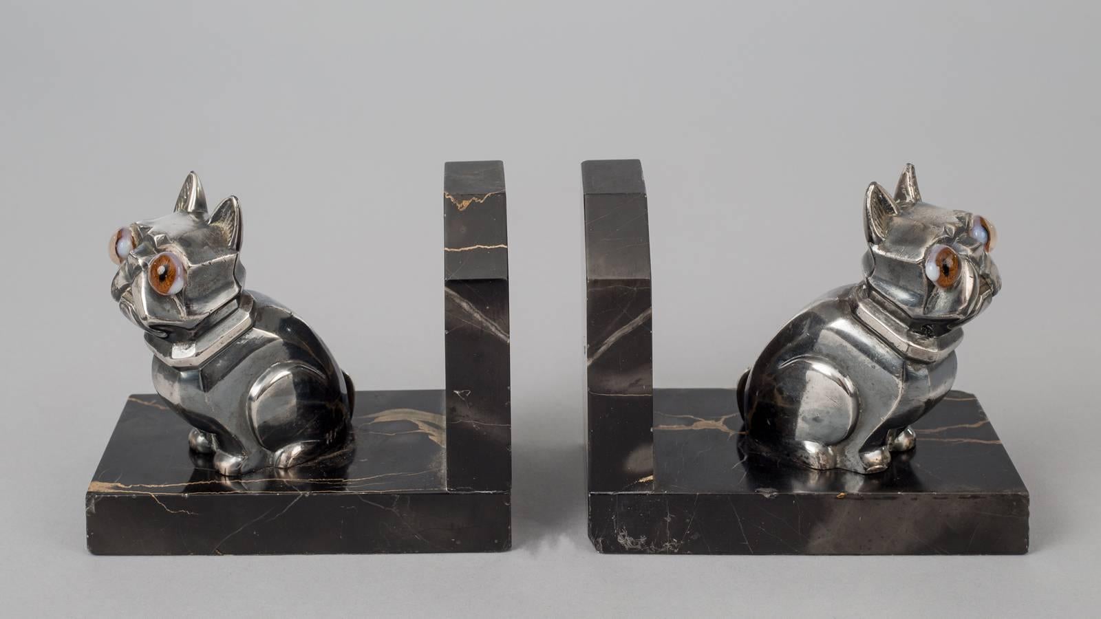 Pair of French Art Deco chromed metal bookends in the form of French bulldogs signed H. Moreau (Hippolyte François Moreau). The dogs have bulging brown glass eyes and are mounted on black marble with gold veins.
