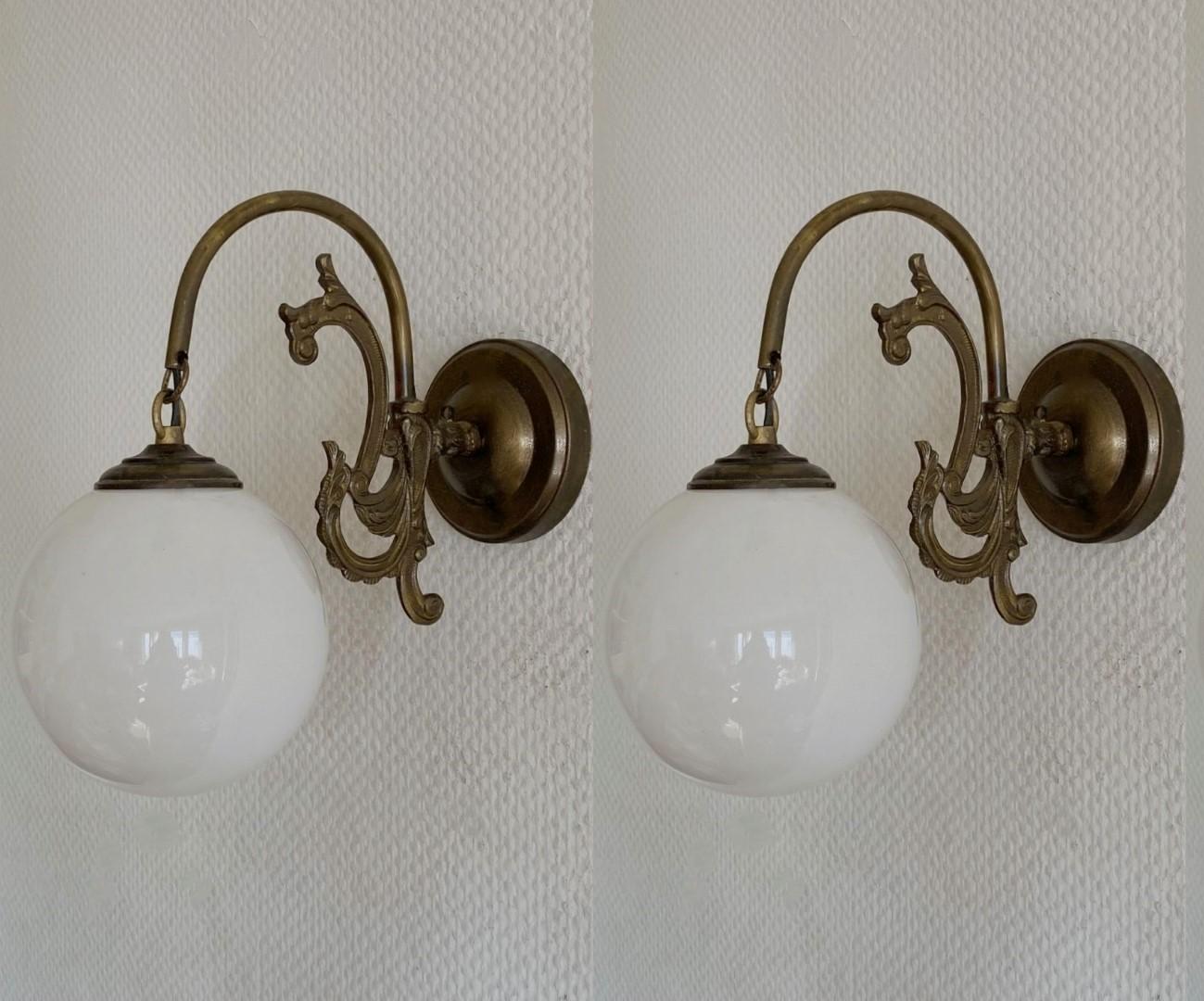 Pair of lovely bronzed brass wall lights with hand-blown opaline glass globes, for indoor or covered outdoor use, France, 1930-1939. Both sconces are in very good condition, beautiful patina, no ships or cracks, rewired. Each sconce takes one Edison
