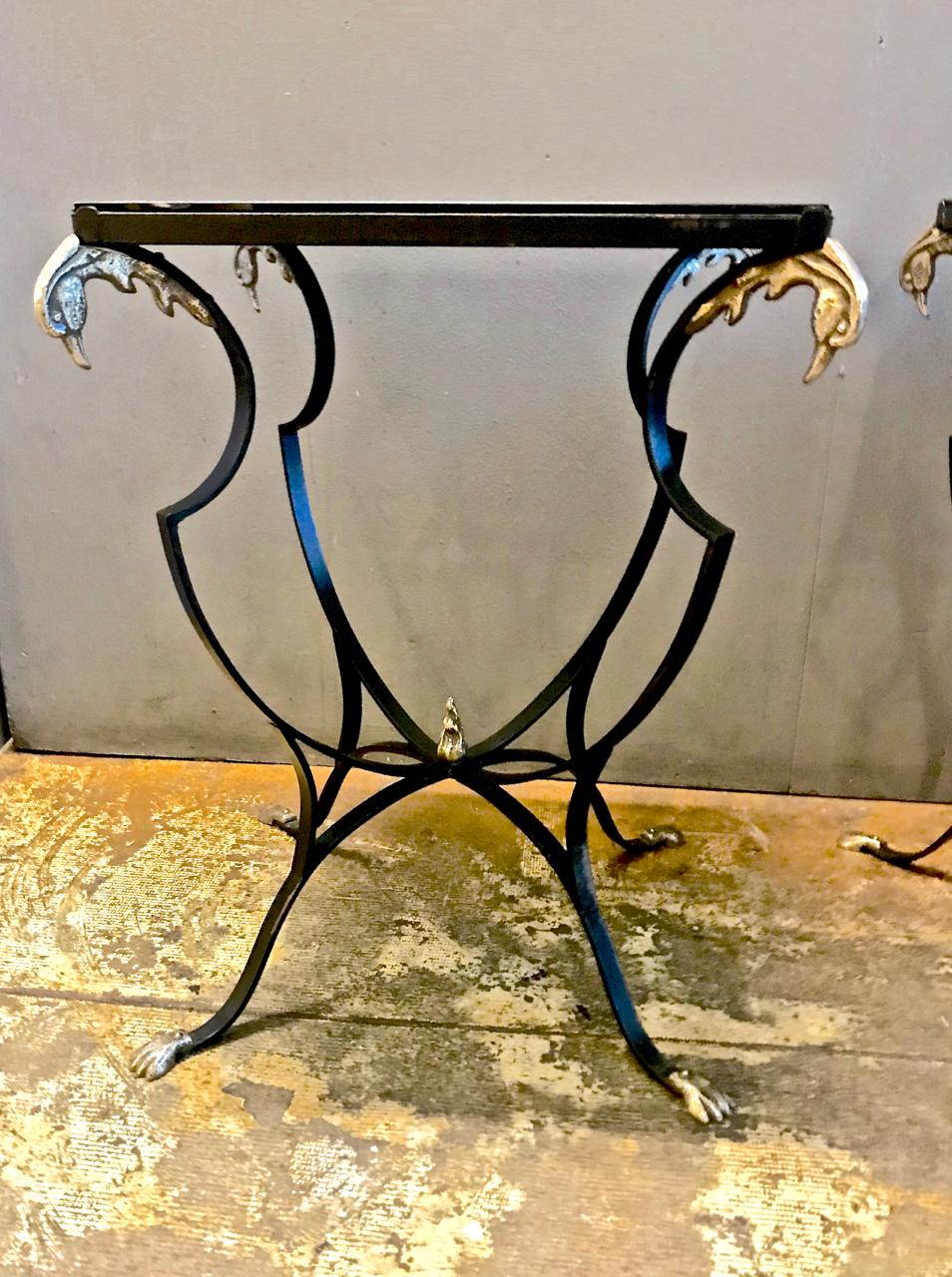 This is a superb pair of early 20th century French forged iron side tables detailed with cast brass phoenix finials and paw feet. The table is in excellent overall original condition with just the right amount of patina. The graceful forged iron