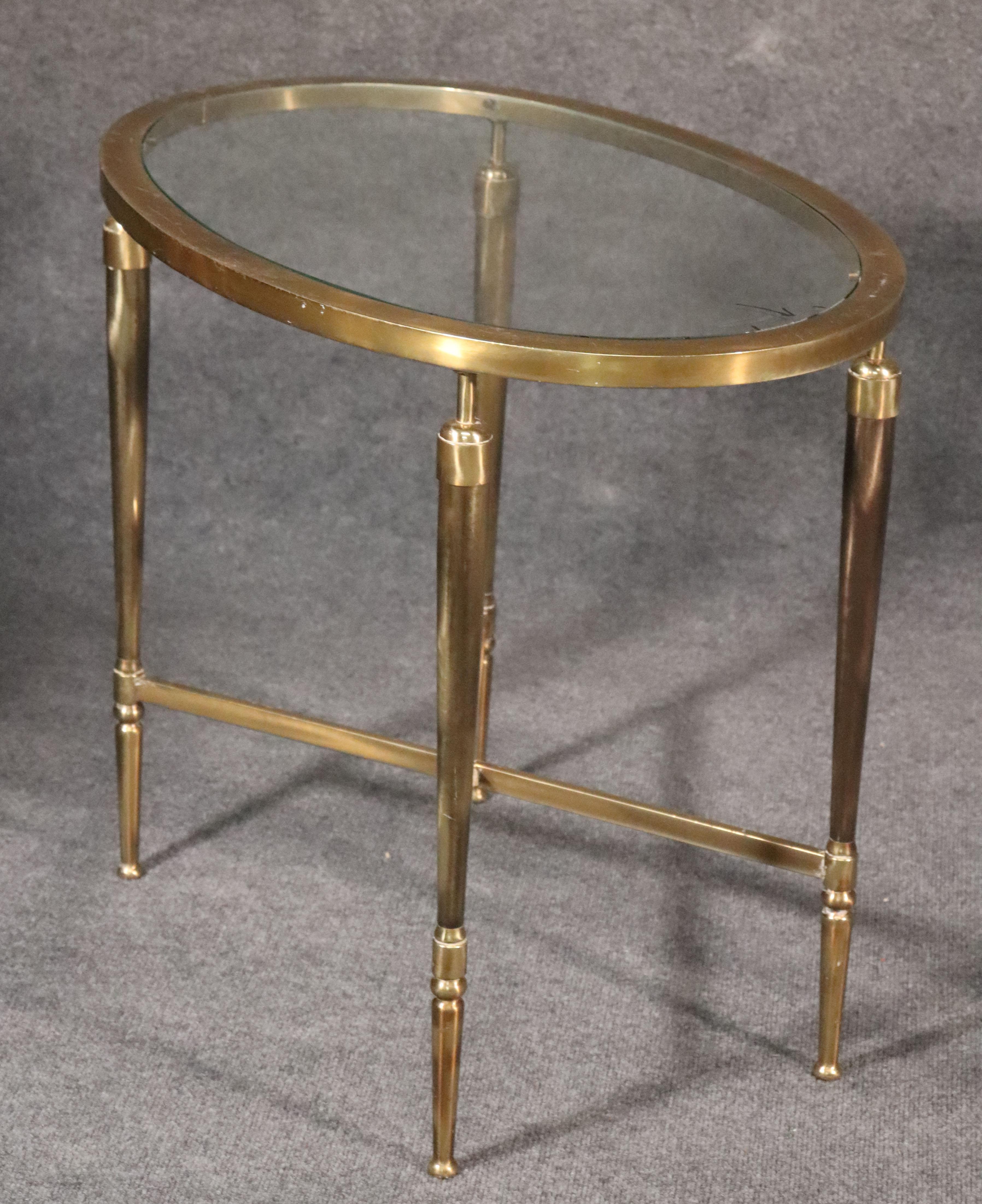 This is a spectacular pair of 1930s French deco tables. They each have new glass tops and great patina on their solid brass frames. They are heavier than they look and have some minor signs of age and surface scuffs from time. The tables measure 25