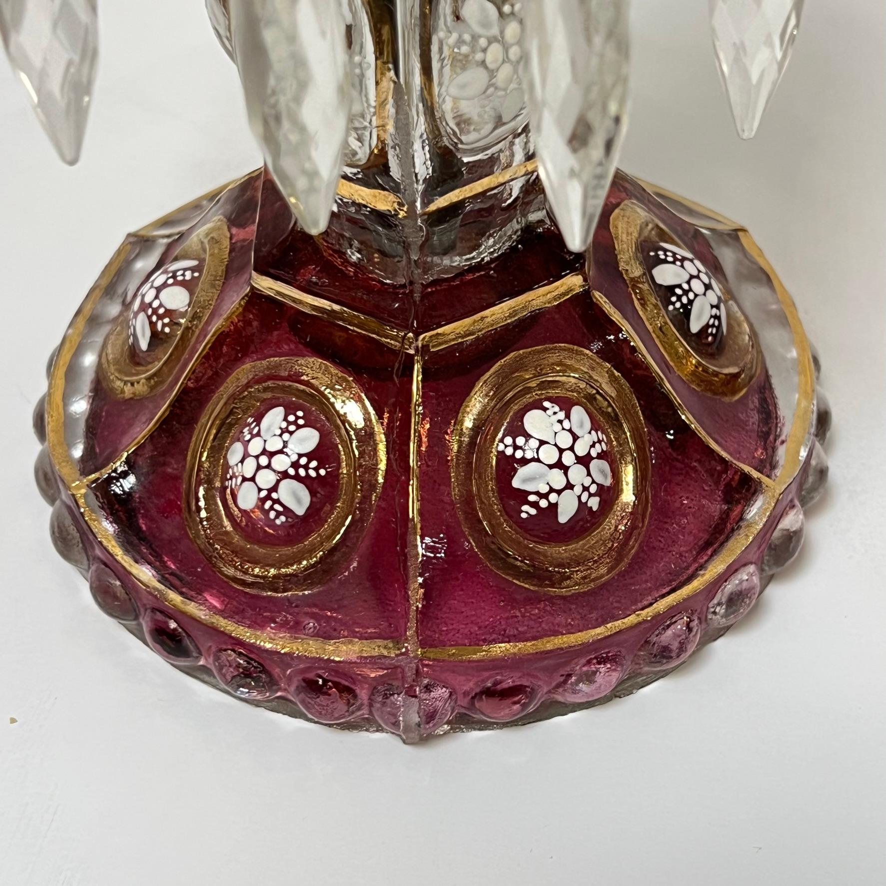 Pair of mid century  candle holders in ruby red glass with gilt and white hand-painted floral designs, and hurricane shades in red-flashed glass with fine painted designs, and gilt engraved designs.  Each in very good condition. 