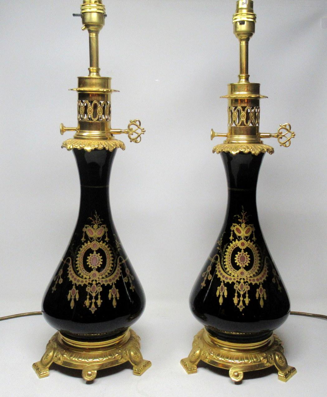 Exceptionally fine pair of French black enameled glass and ormolu-mounted fluid lamps, now converted to electricity, early to mid-19th century.

The twin original ormolu part burners with lavish pierced decoration above a bell shaped body with