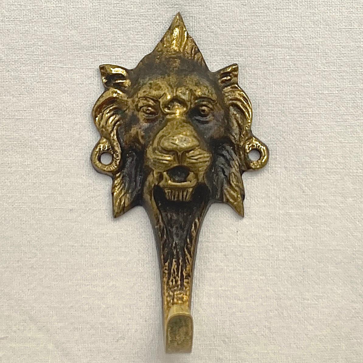 Pair of French brass single hooks with a detailed lion head design, the hooks have a lovely black patina finish. They have two holes on each lion for wall mounting. Measuring length 8cm / 3.1 inches by maximum width 4.3cm / 1.7 inches. There is wear