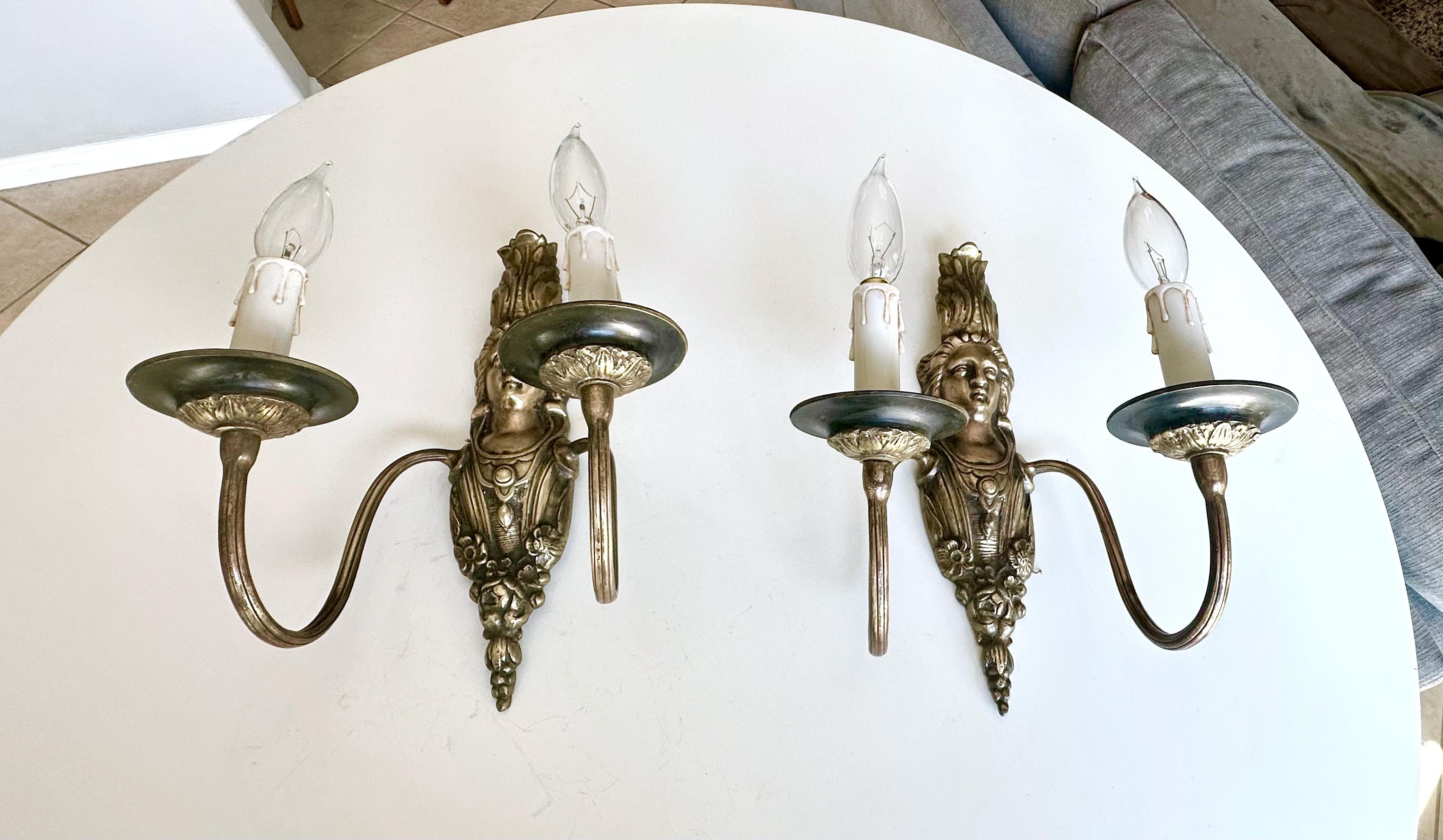 Pair French Neoclassic style two-arm brass wall sconces with classical female motif and other design elements characteristic of French aesthetics. Newer wiring for US installation. 