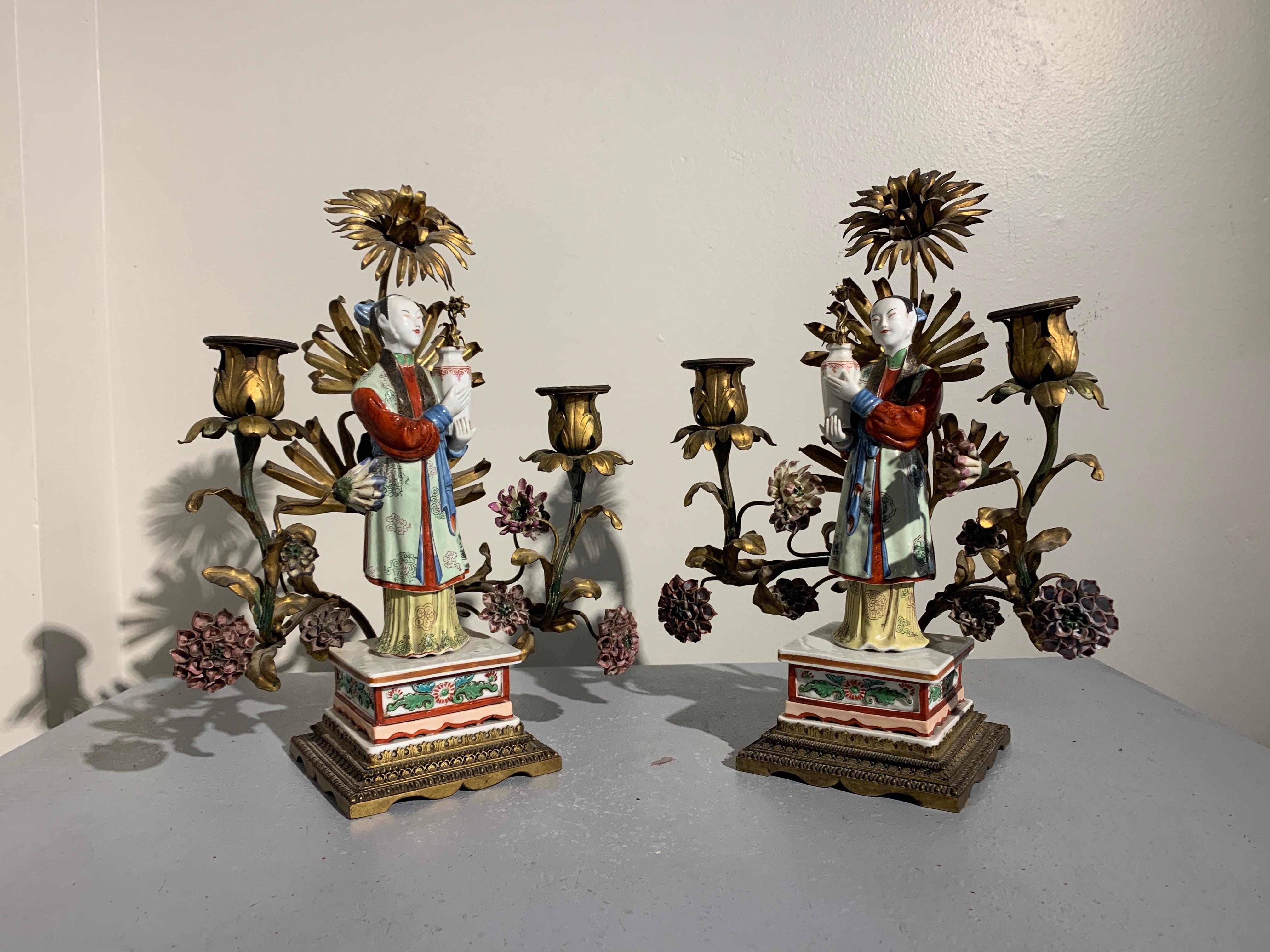 A delightful pair of French Chinoiserie gilt metal and porcelain two arm candelabra, early 20th century, with the porcelain figures attributed to Samson et Cie, Paris. 

The candelabra feature a matched pair of Chinese Export style famille rose