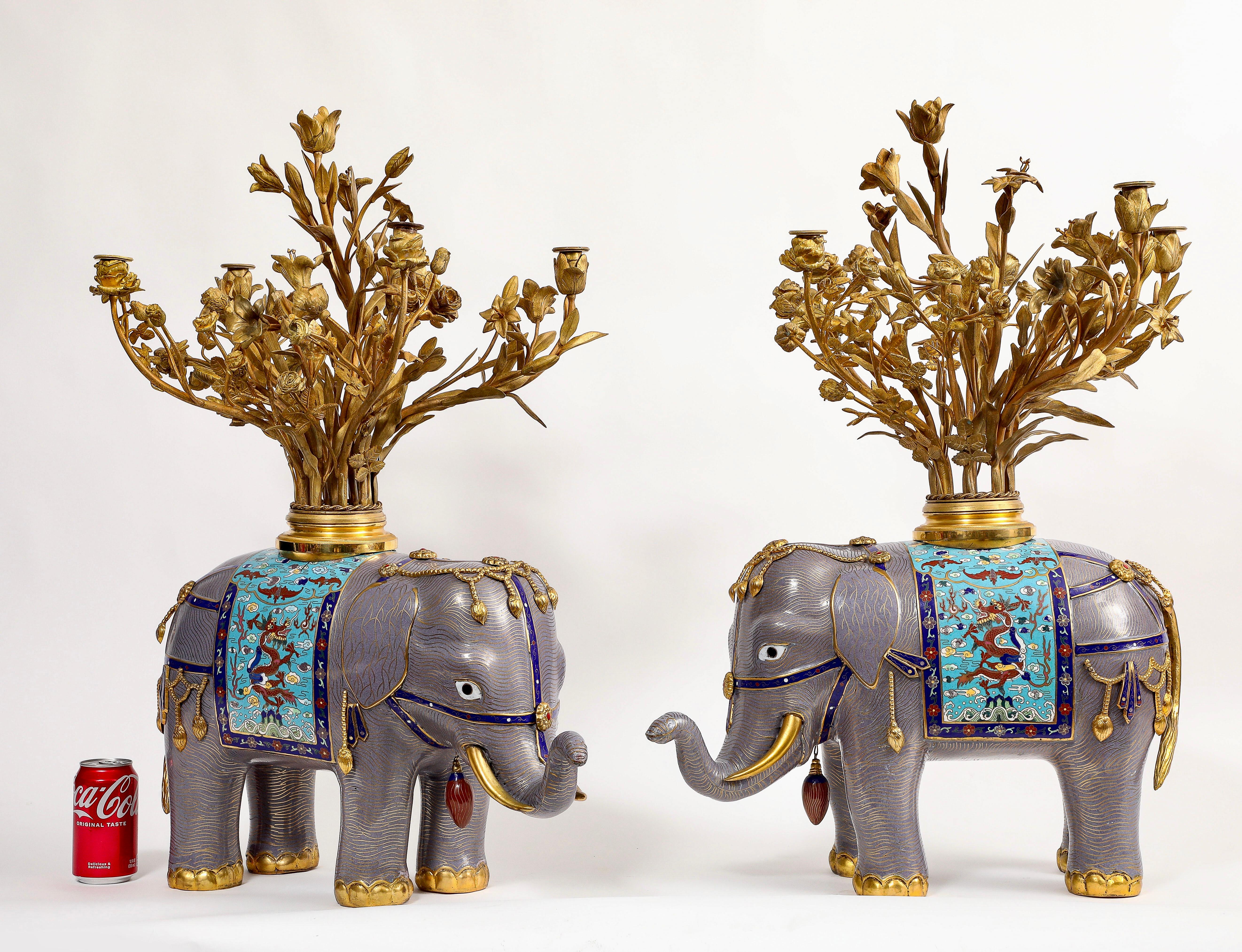 Un'imponente e insolita coppia di candelabri in stile Luigi XV francese del XIX secolo in bronzo dorato e cloisonné cinese a forma di elefante. Ogni elefante è caratterizzato da elaborati rami floreali in ormolu francese, è modellato con proboscidi